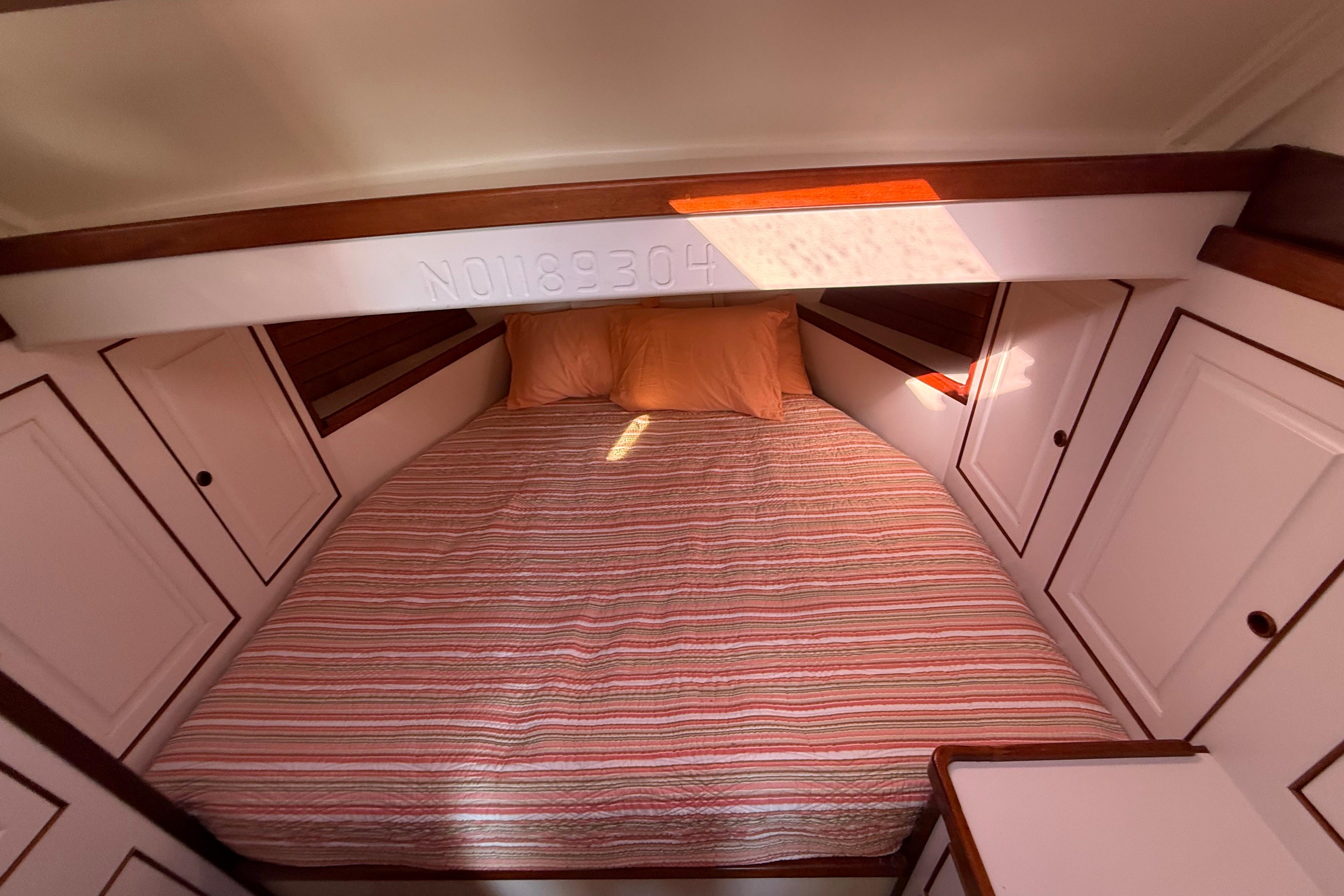 Cozy cabin interior of 2006 Mast & Mallet Thomas Point 40 with striped bedding.