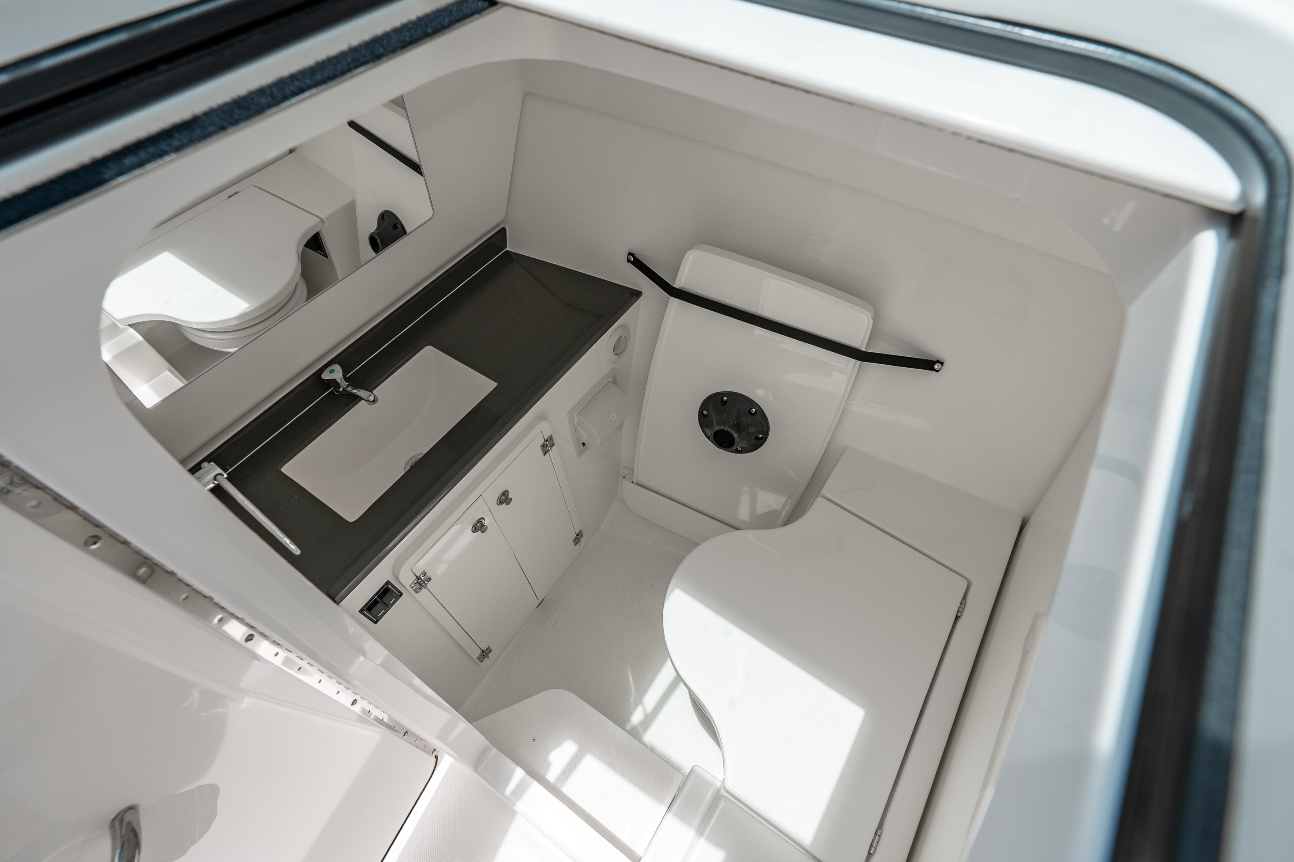 Interior of 2026 Pursuit DC 326 Dual Console boat, featuring a compact bathroom.