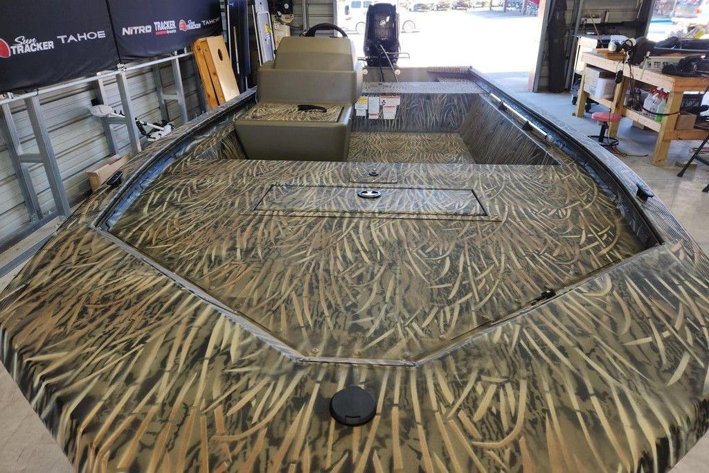 2026 Tracker Grizzly 1648 SC boat with camouflage design in a workshop setting.