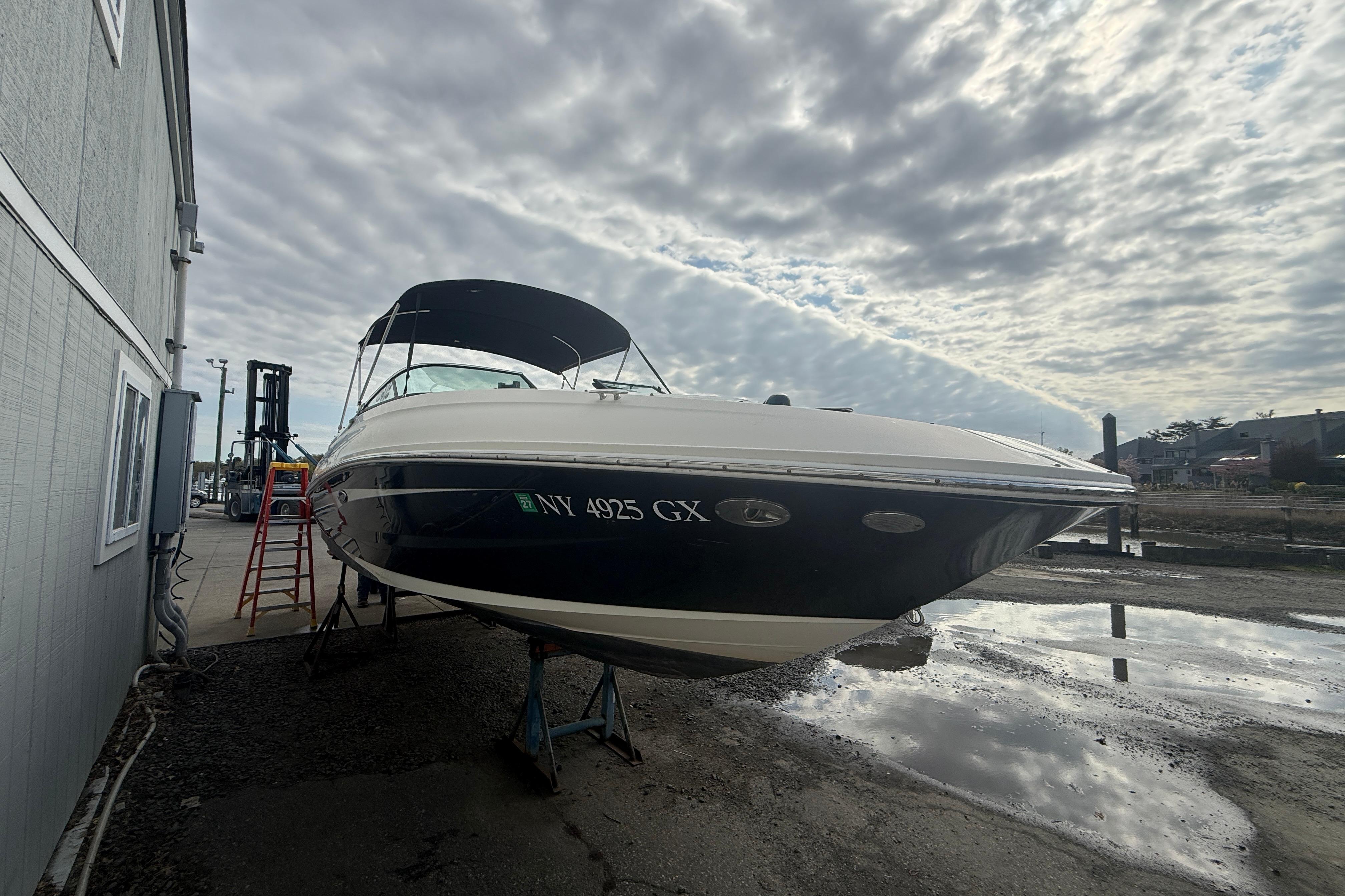 2015 Sea Ray 240 Sundeck boat on land, cloudy sky background.
