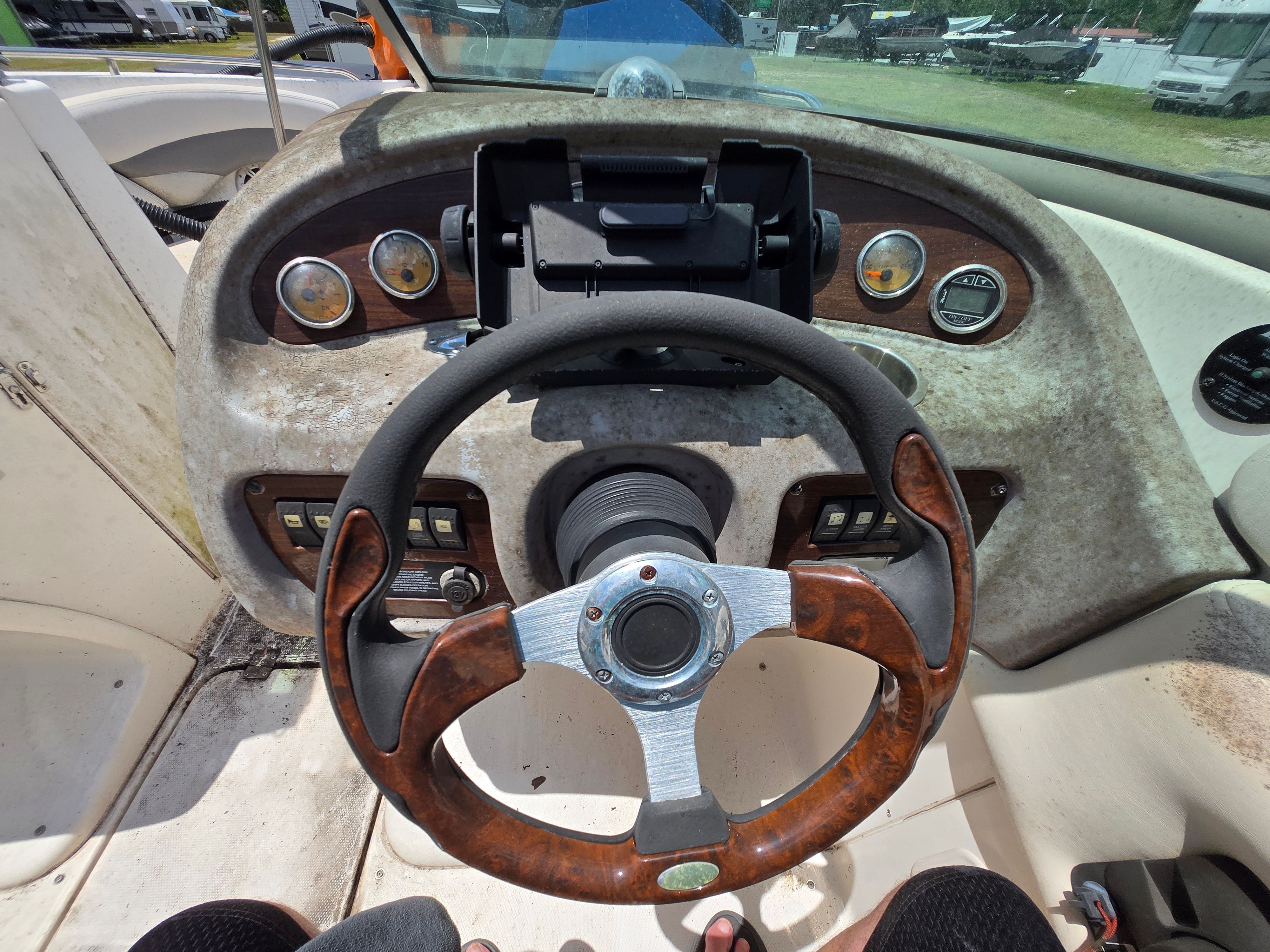 The image shows the dashboard of a 2006 Chaparral 220 SSi boat with a wooden steering wheel.
