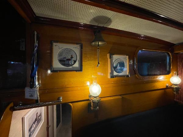 1951 Chris-Craft Catalina interior with framed pictures, vintage lamps, and wooden paneling.