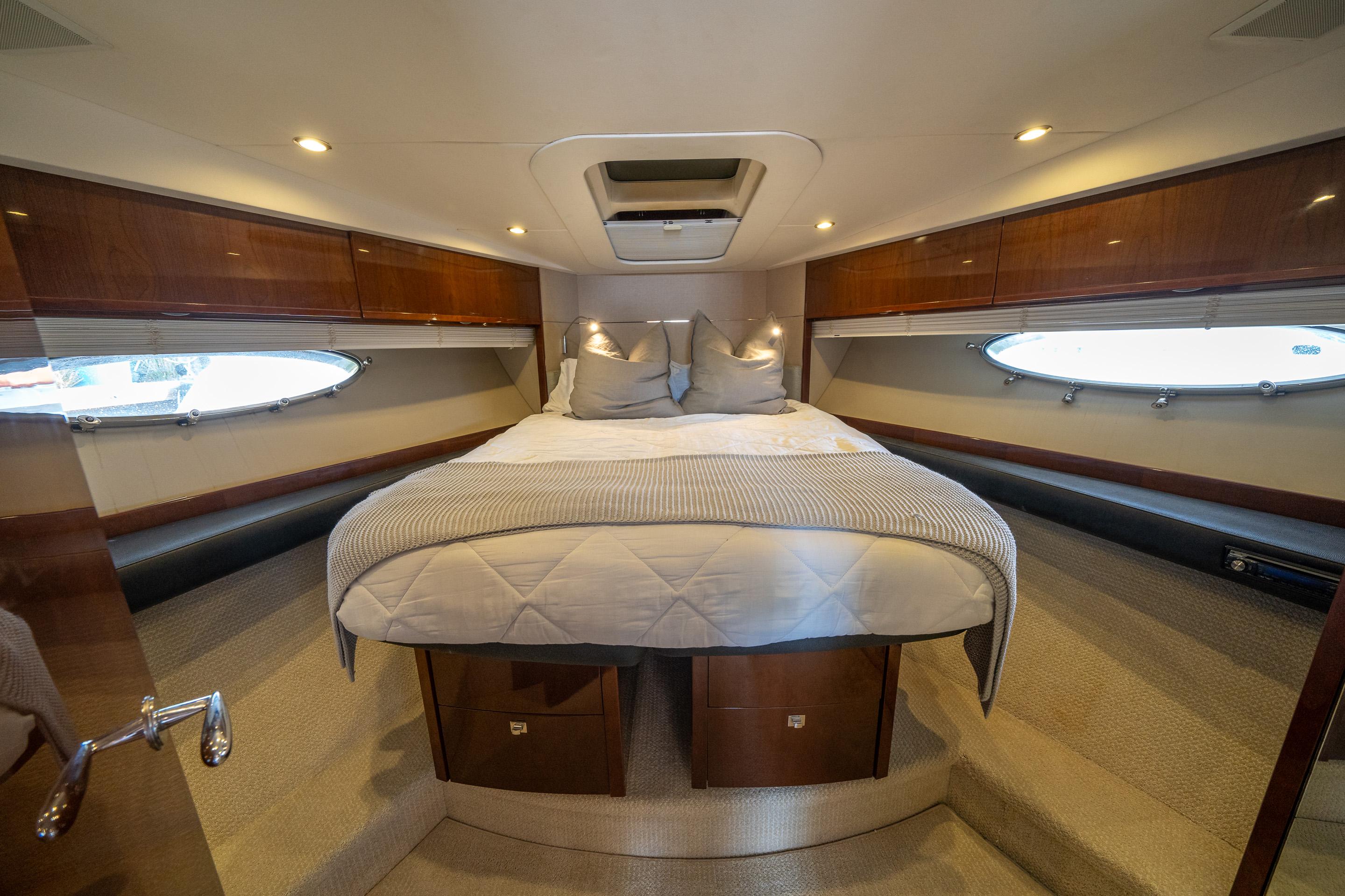 Luxurious 2012 Princess V52 yacht cabin with elegant wood finishes and cozy bedding.