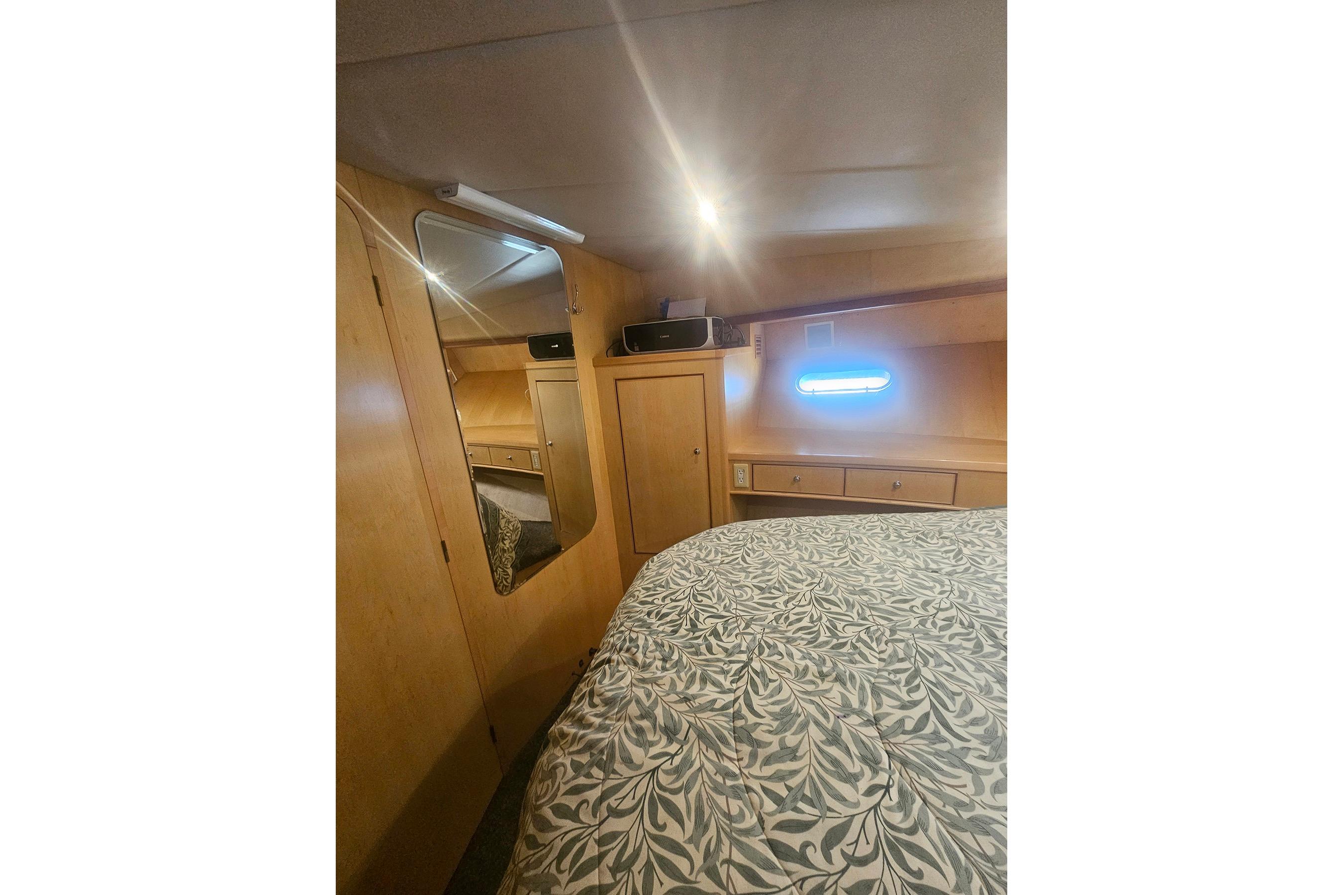 Cozy bedroom interior in a 1995 Symbol 55 yacht, featuring wood paneling and patterned bedding.