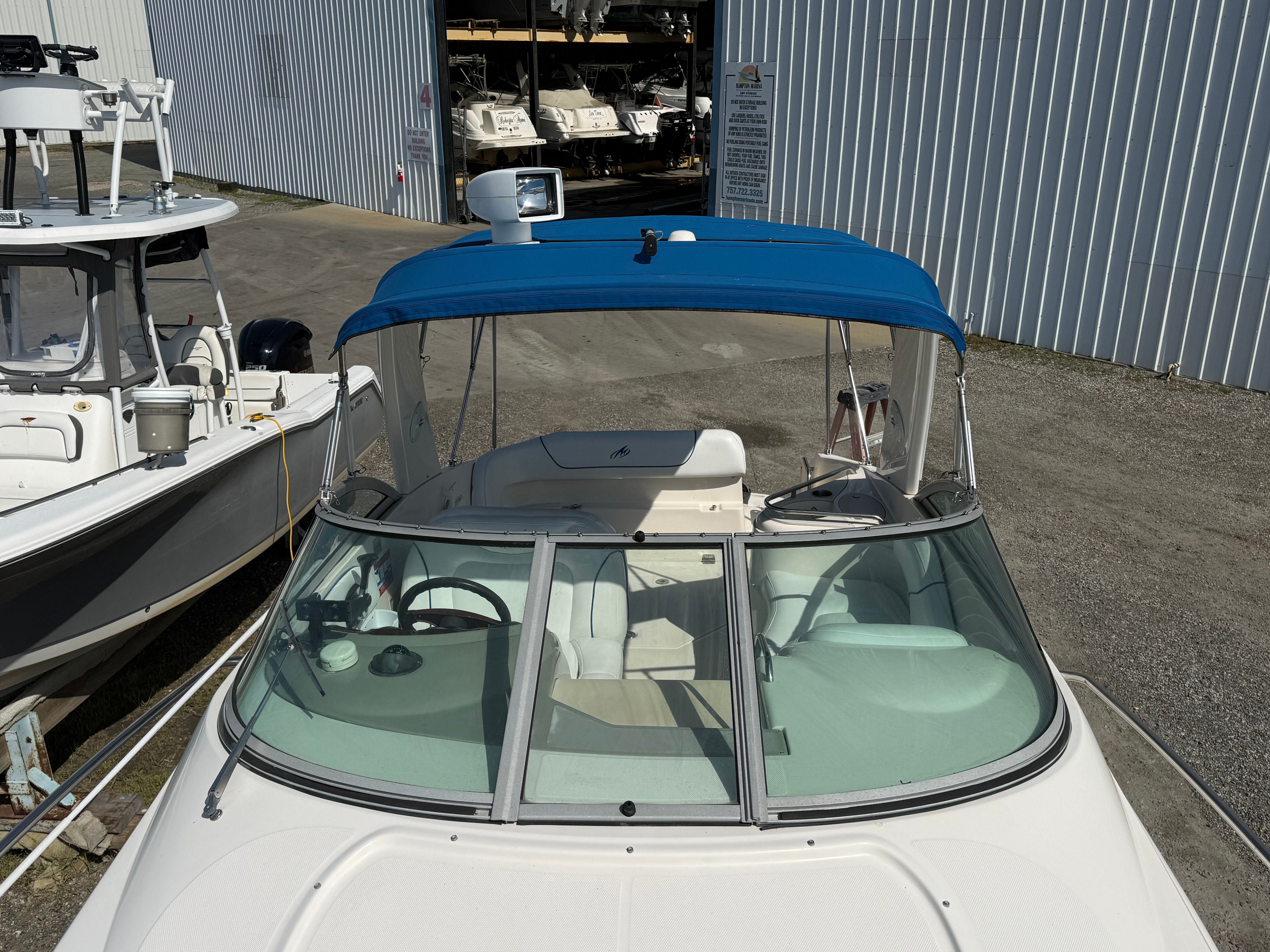 A 2006 Monterey 270 Cruiser with a blue canopy, parked next to other boats.