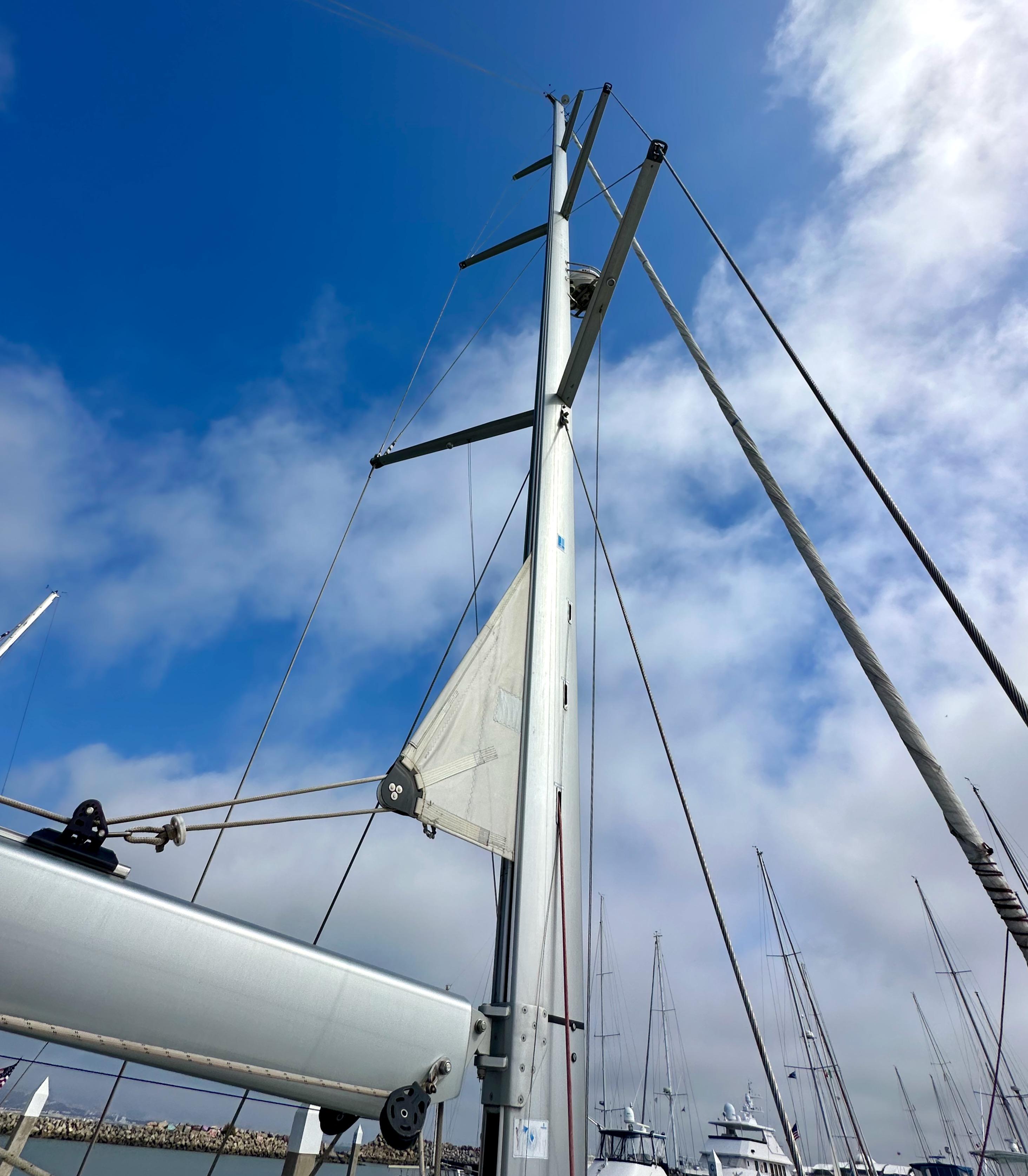 Mast of 2014 Jeanneau 57 sailboat against a cloudy blue sky.