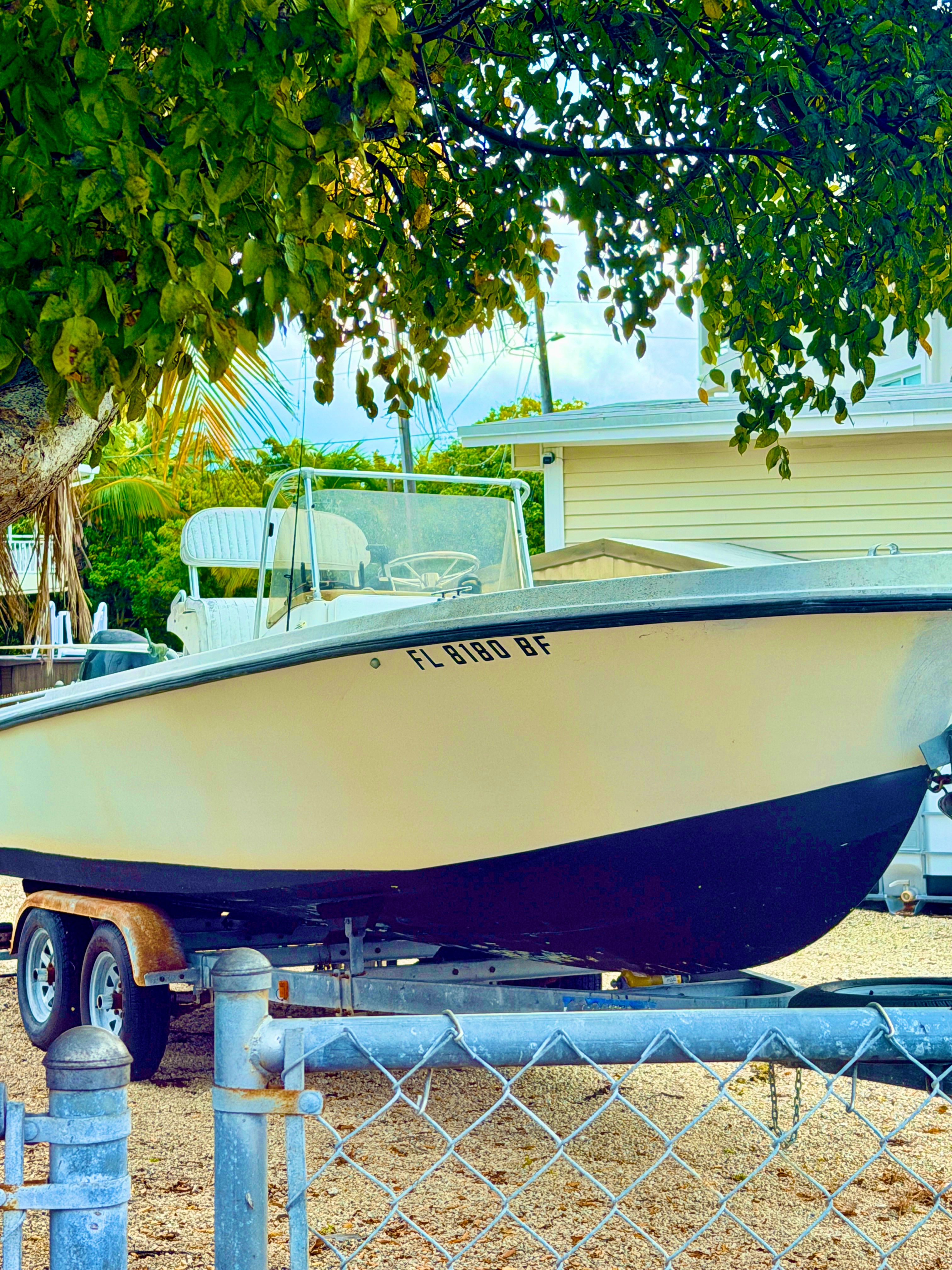 1970 Mako 20 boat on trailer under tree.