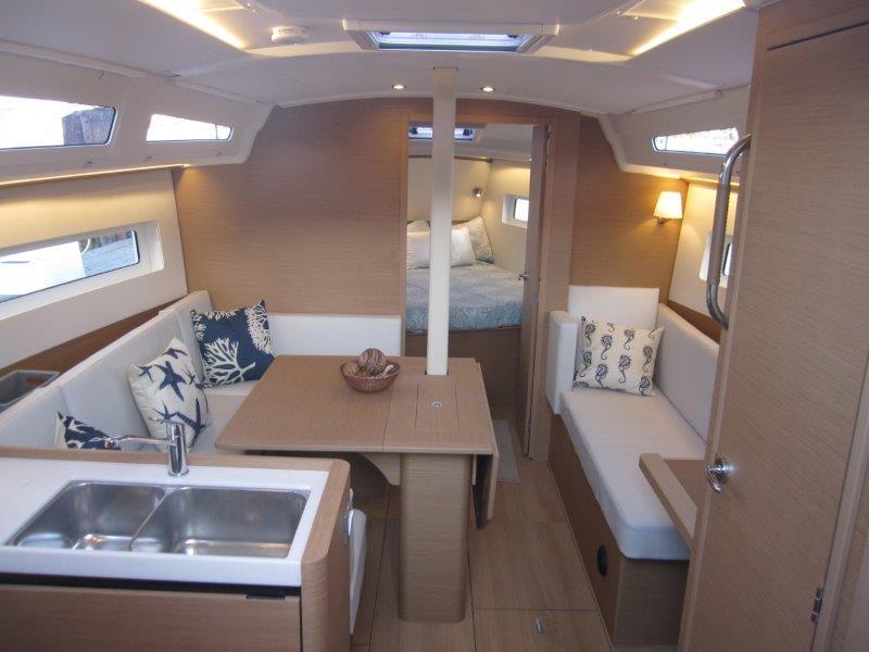 Modern interior of 2024 Jeanneau 380 sailboat with cozy seating and dining area.
