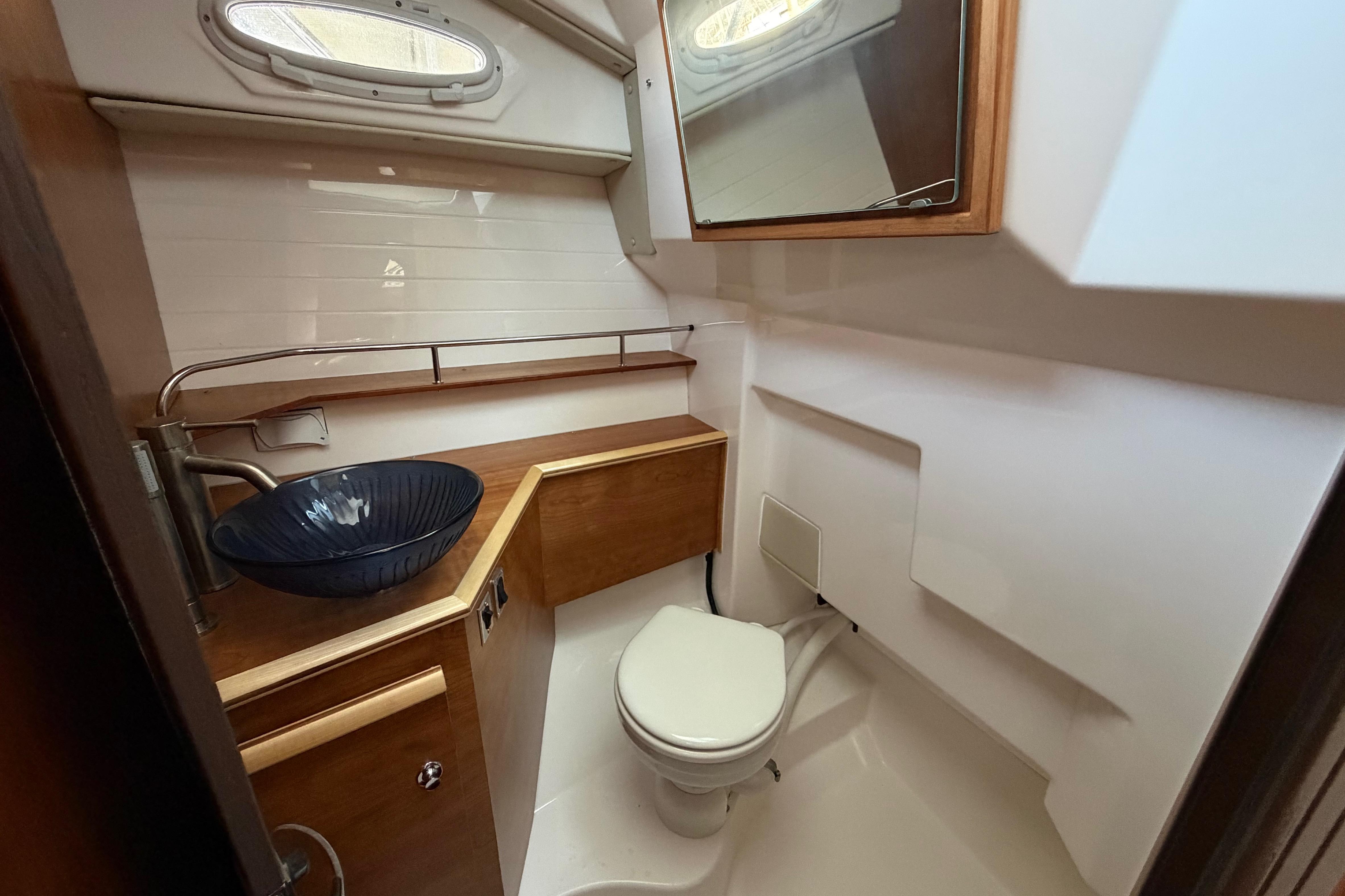 2023 Cutwater C-288 Coupe bathroom with modern sink, toilet, and wooden cabinetry.