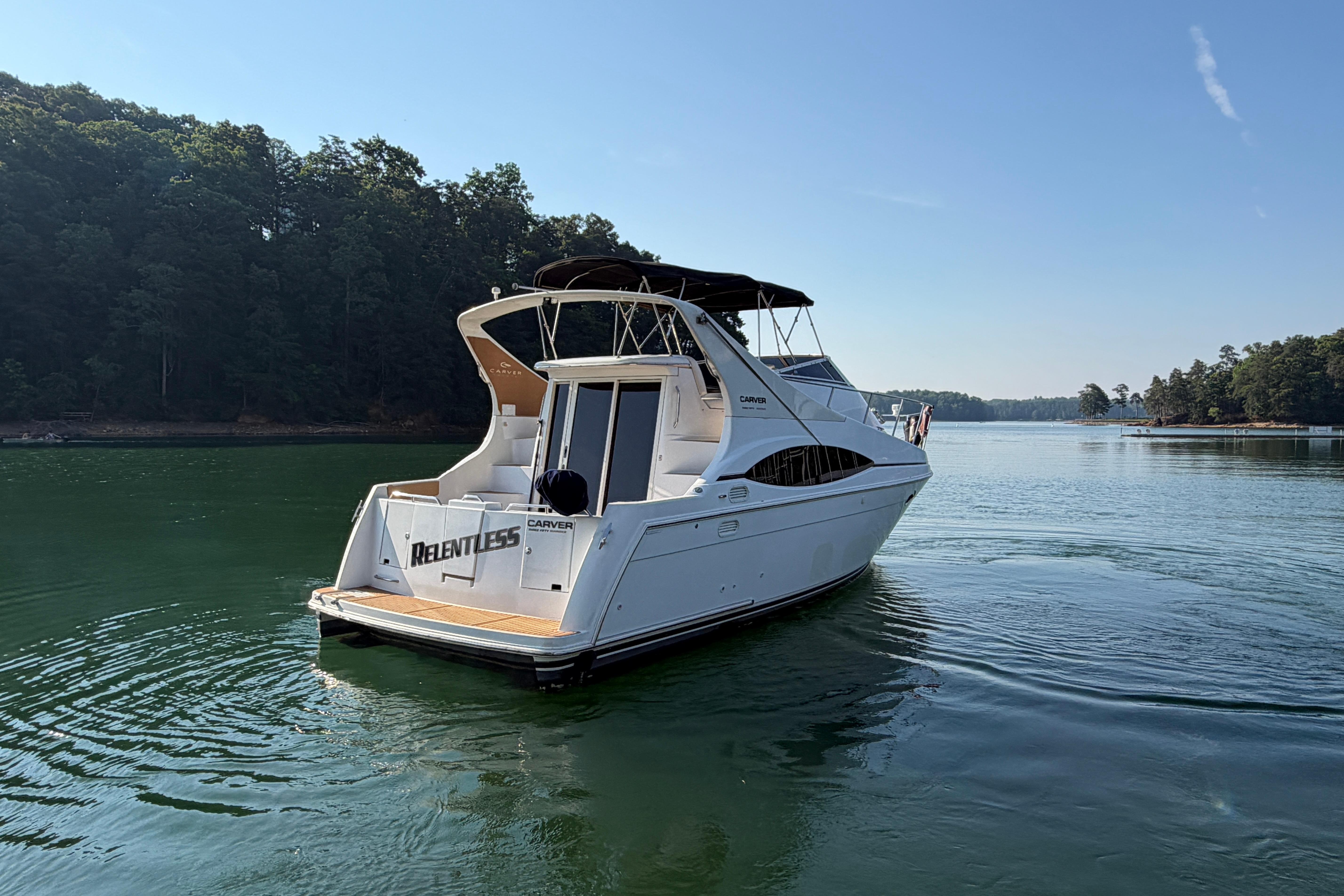 2003 Carver 350 Mariner yacht on serene lake with lush forest backdrop.