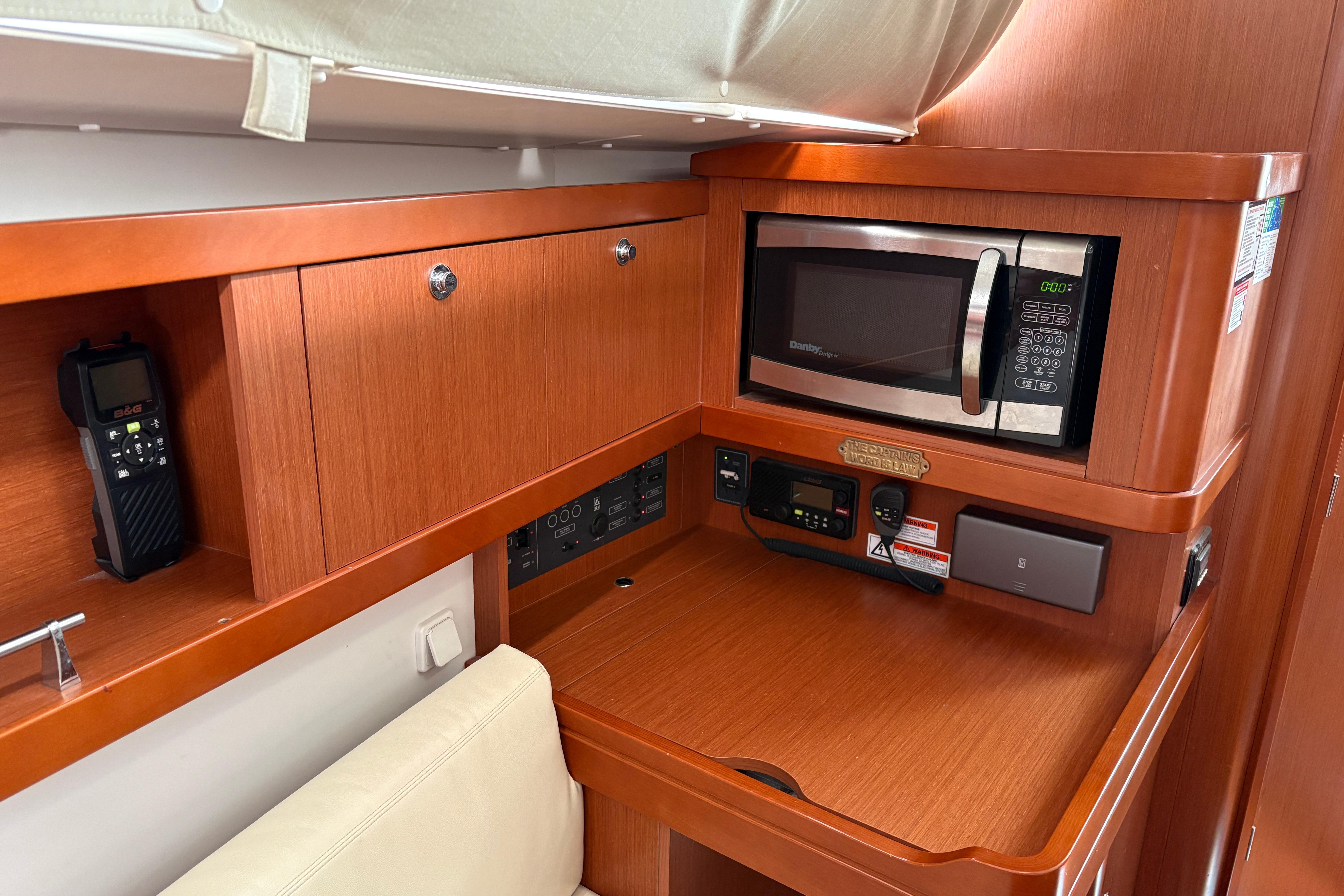 Interior of 2015 Beneteau Oceanis 34 yacht with microwave and wooden cabinetry.