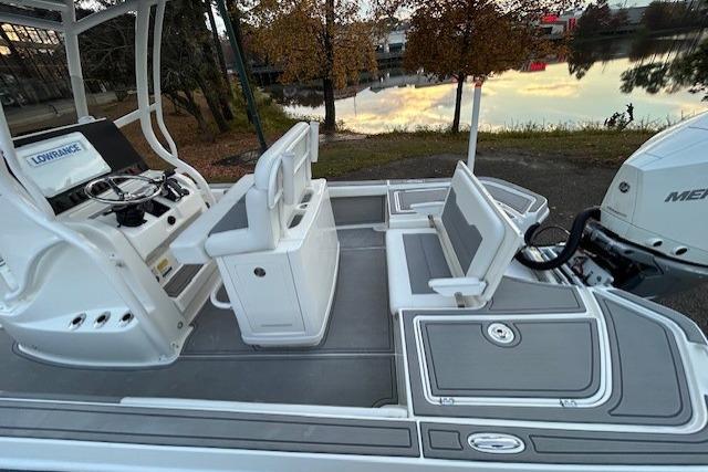 2025 Mako 24 APEX boat interior with seating and control panel by a lake.