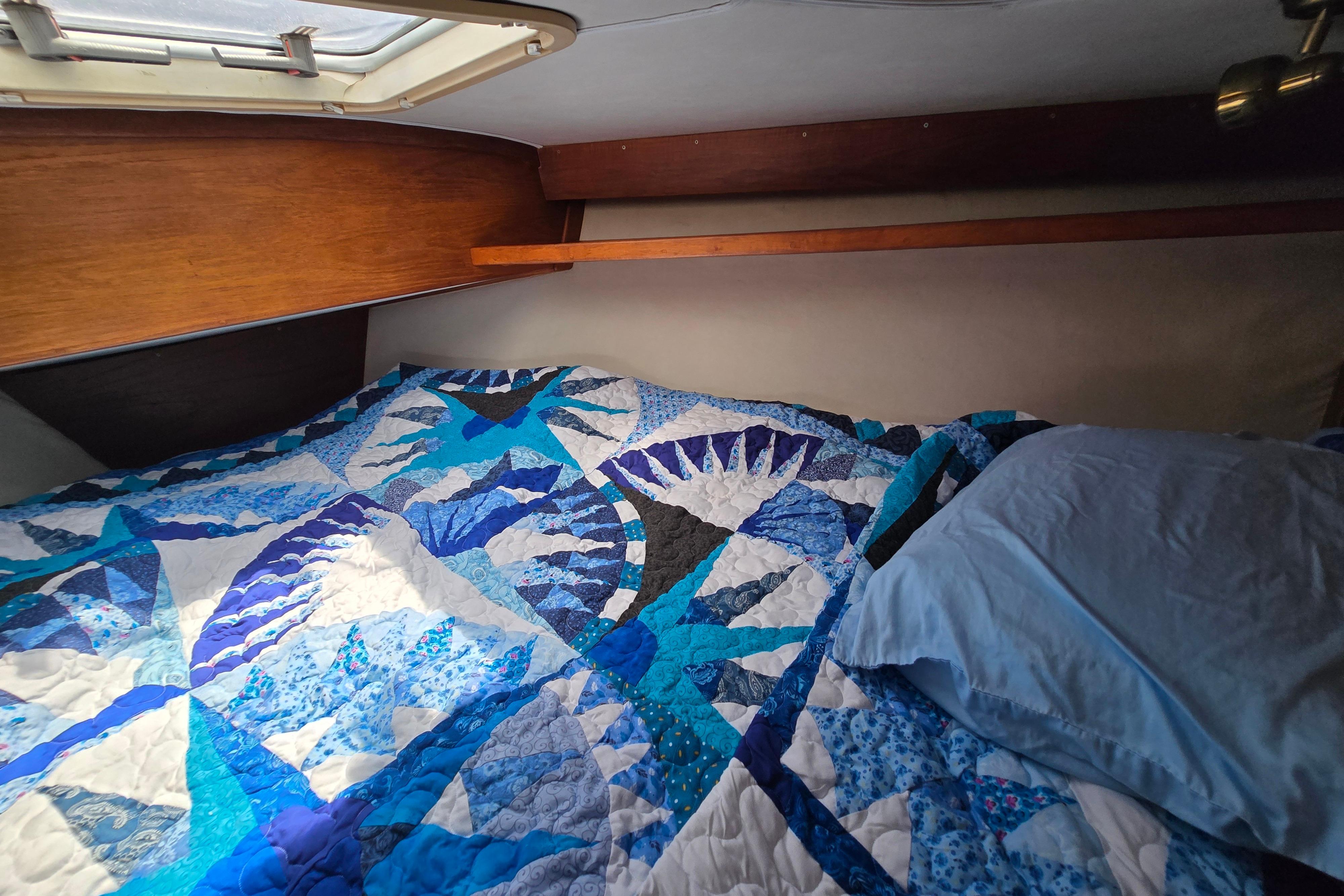 Cozy cabin bed in 1993 Caliber 35 sailboat with blue quilt and pillow.