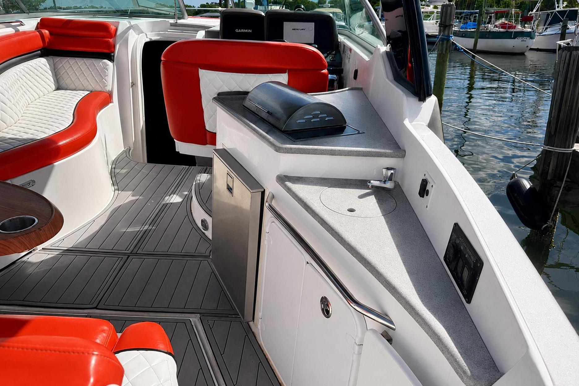 2012 Rinker 310 Express Cruiser LE interior with red and white seating, kitchenette, and water view.