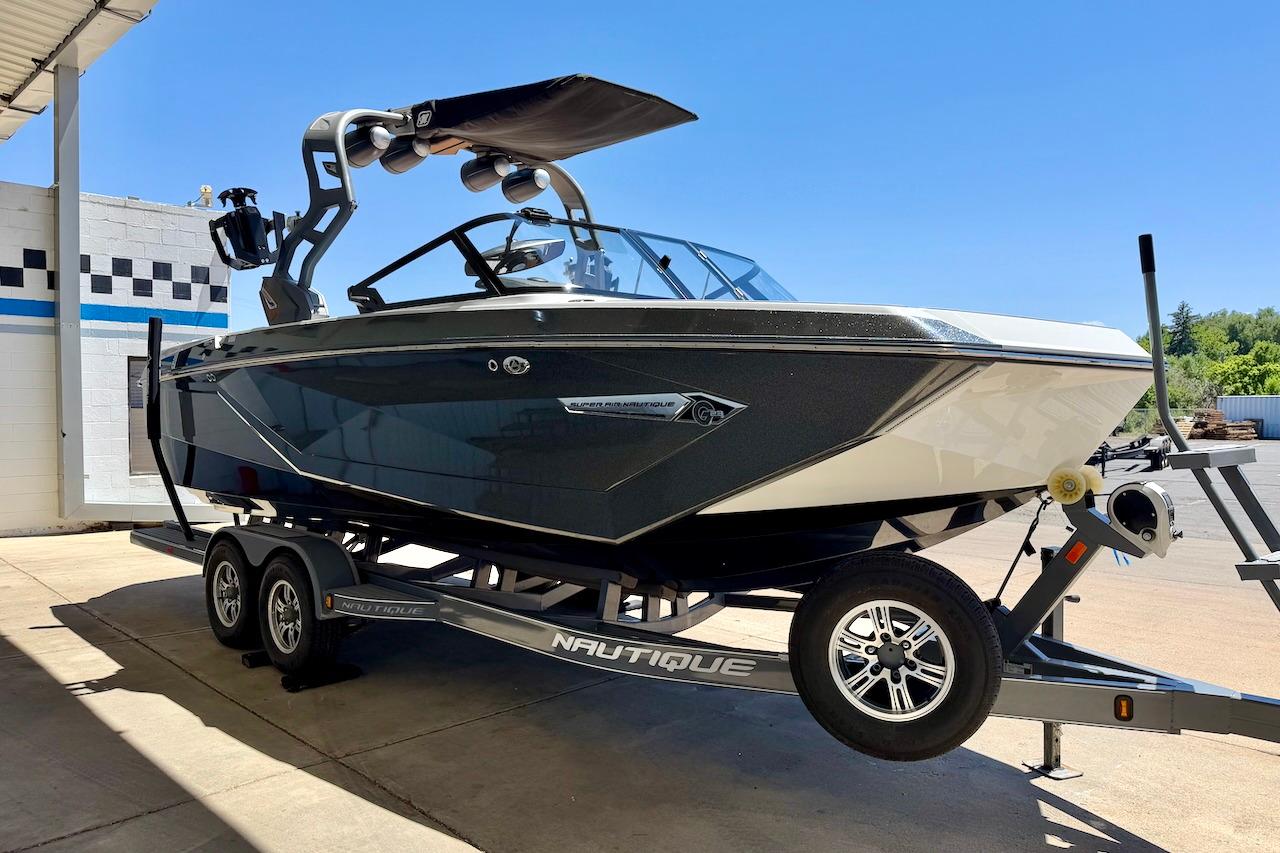 2021 Nautique Super Air Nautique G23 boat on trailer, parked outdoors under clear blue sky.
