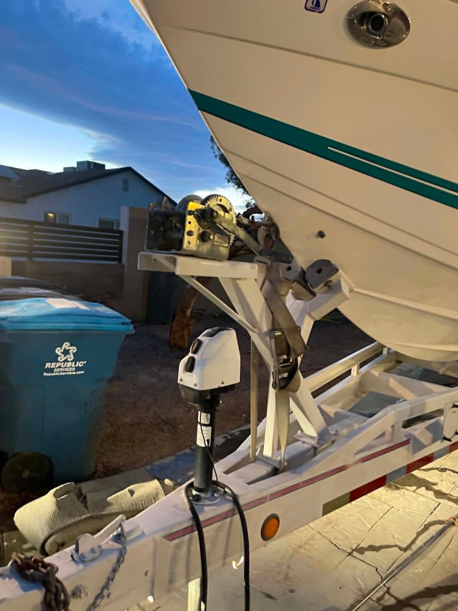 A boat on a trailer in a driveway at sunset.