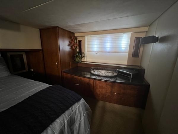 Luxurious bedroom interior of 2009 Ovation 52 yacht with wooden cabinetry and window.
