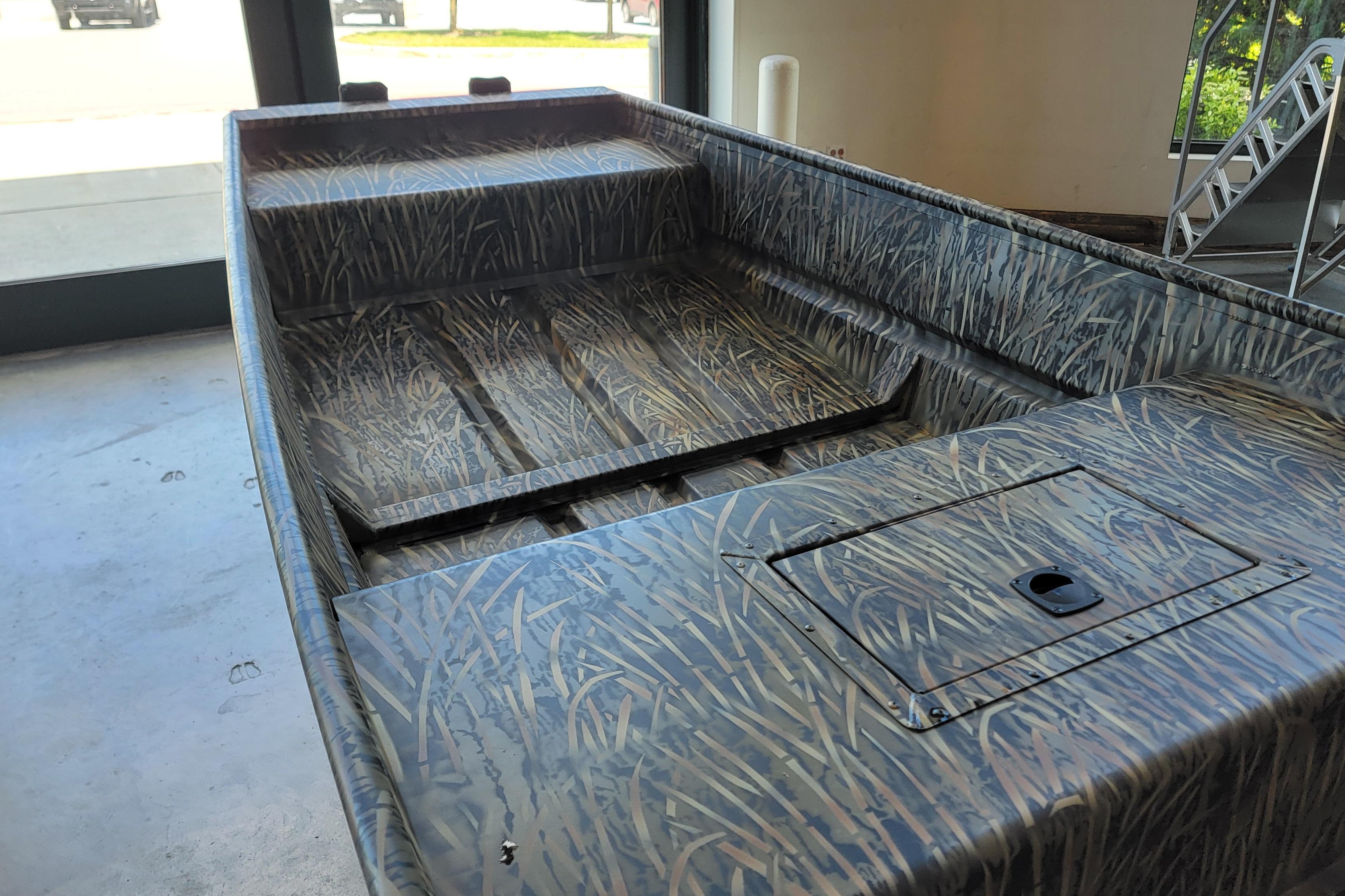 2026 Tracker Grizzly 15 Jon boat with camouflage design in a showroom.