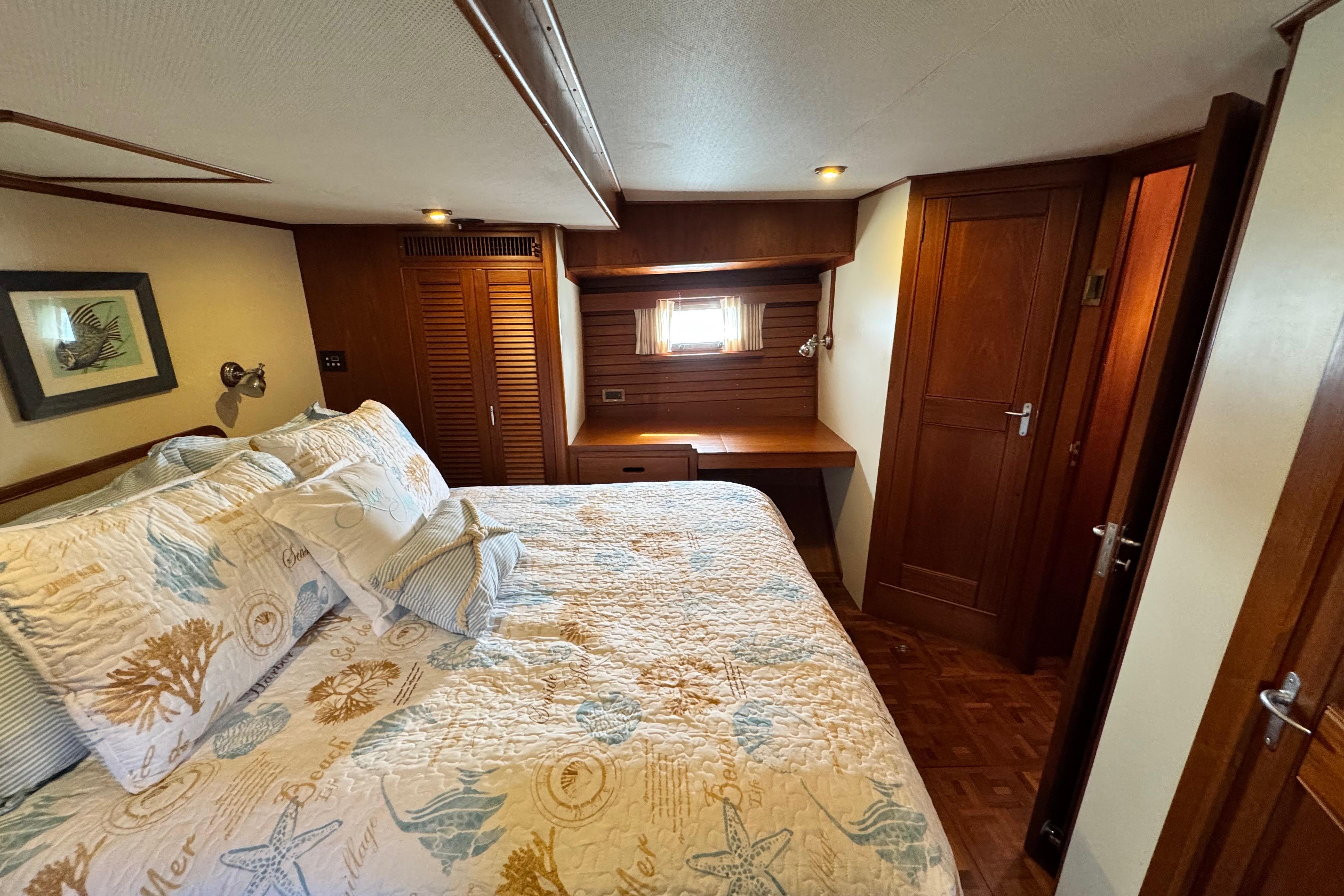 Luxurious cabin interior of 2000 Grand Banks 52 Europa yacht with cozy bedding and wooden decor.