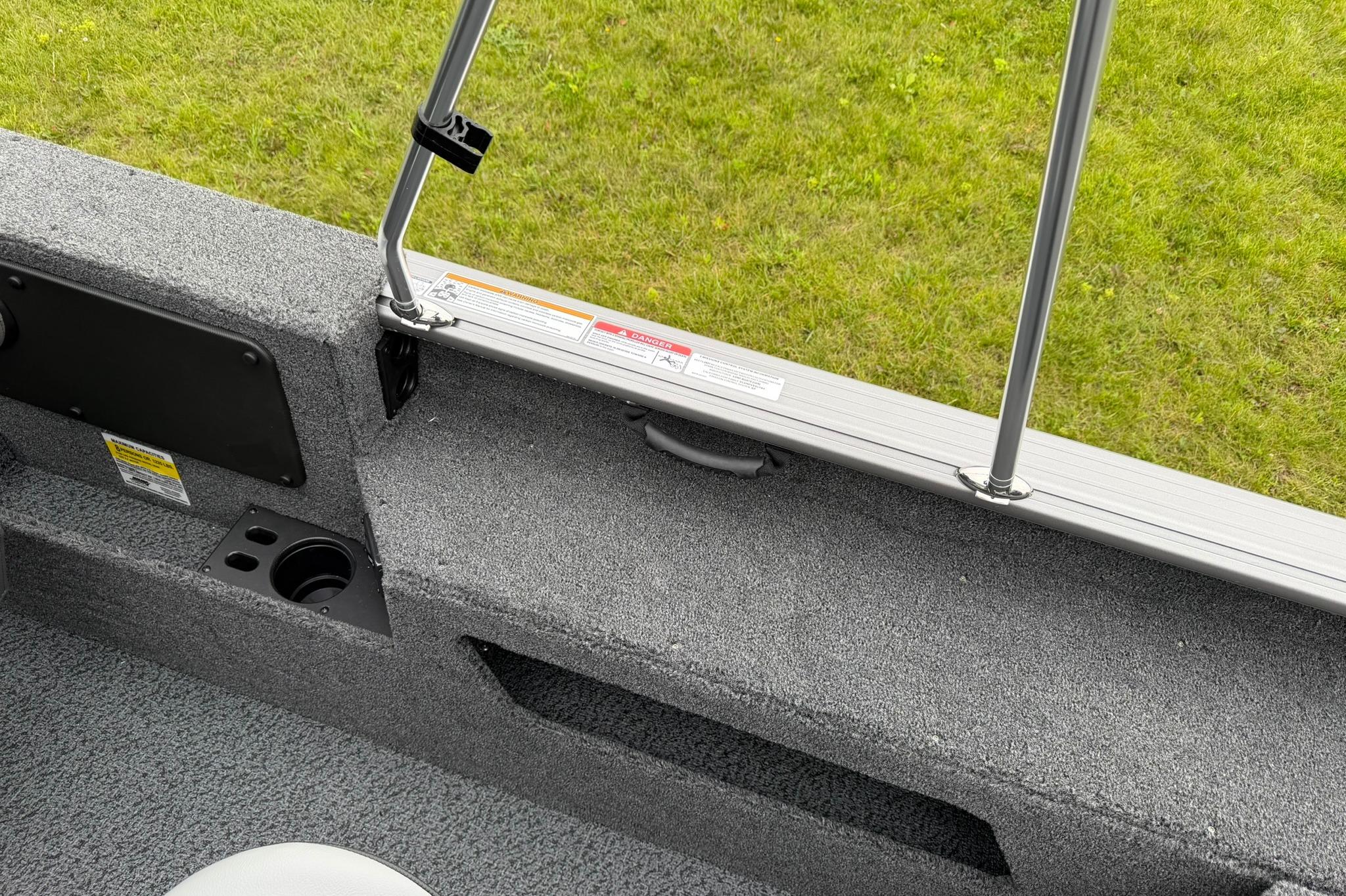 Interior view of 2027 Lund 2075 Impact XS boat, featuring carpeted surface and cup holder.
