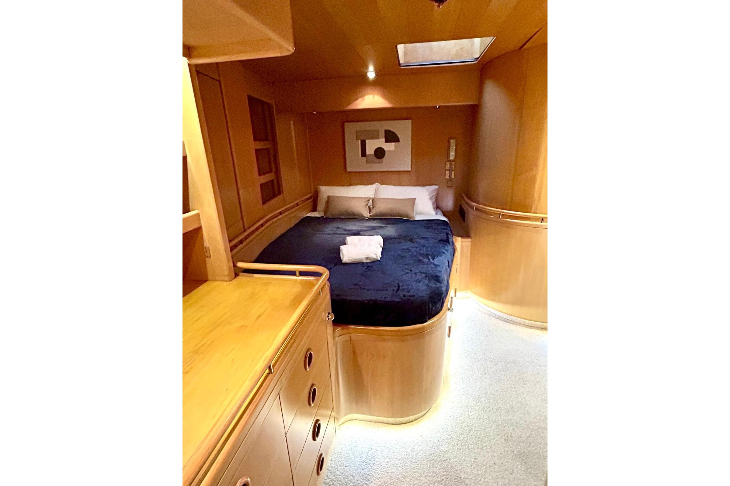 Luxurious yacht bedroom with wooden interior, cozy bed, and modern design, 1989 Ron Holland Design.