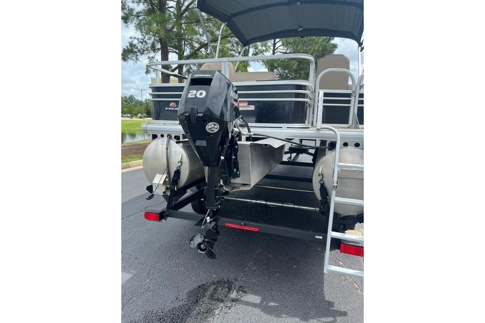 2023 SUNTRACKER Fishing Barge 20 with Mercury outboard motor, parked on pavement.