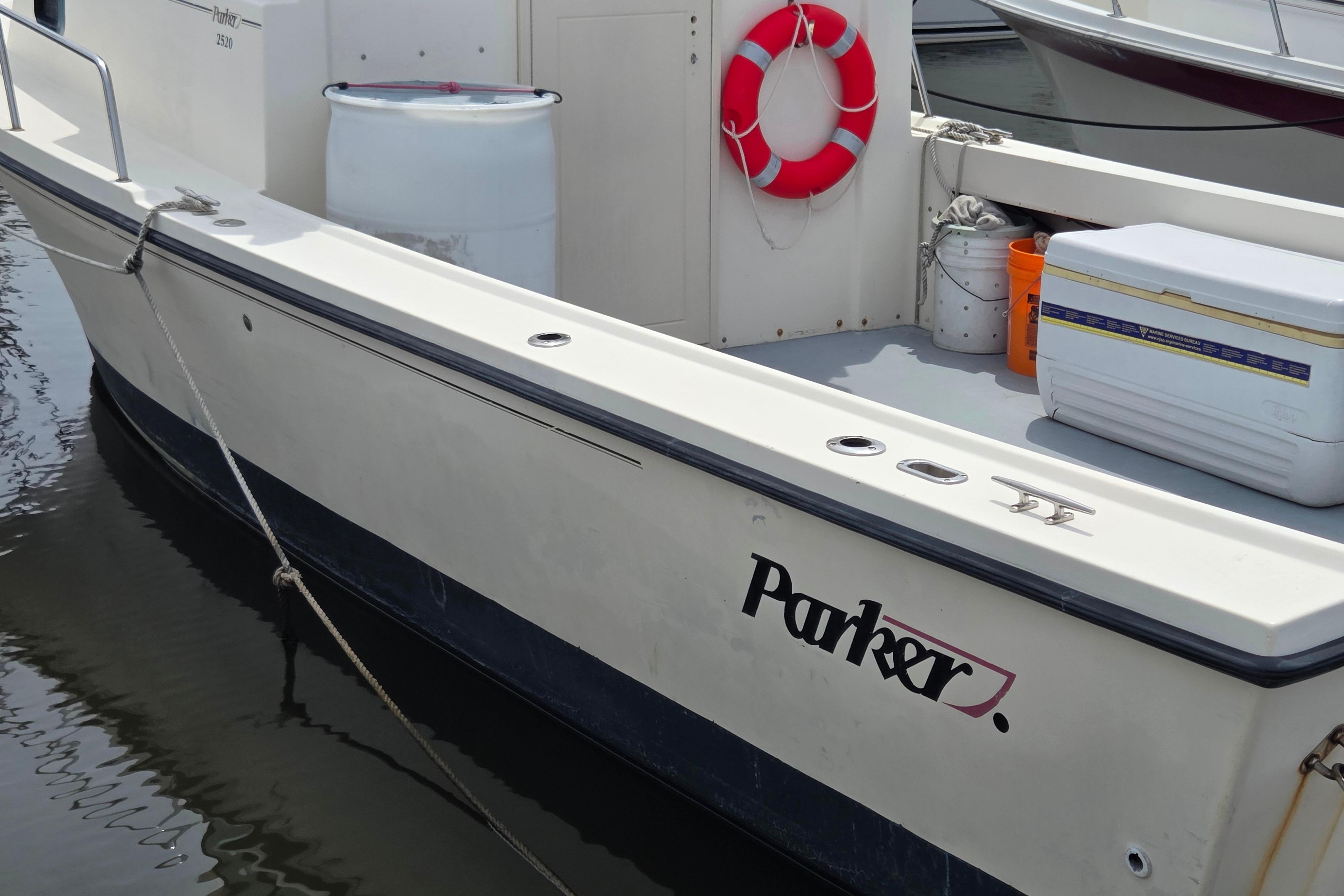 2002 Parker 2520 Deep Vee Sport Cabin boat docked with life preserver and cooler.