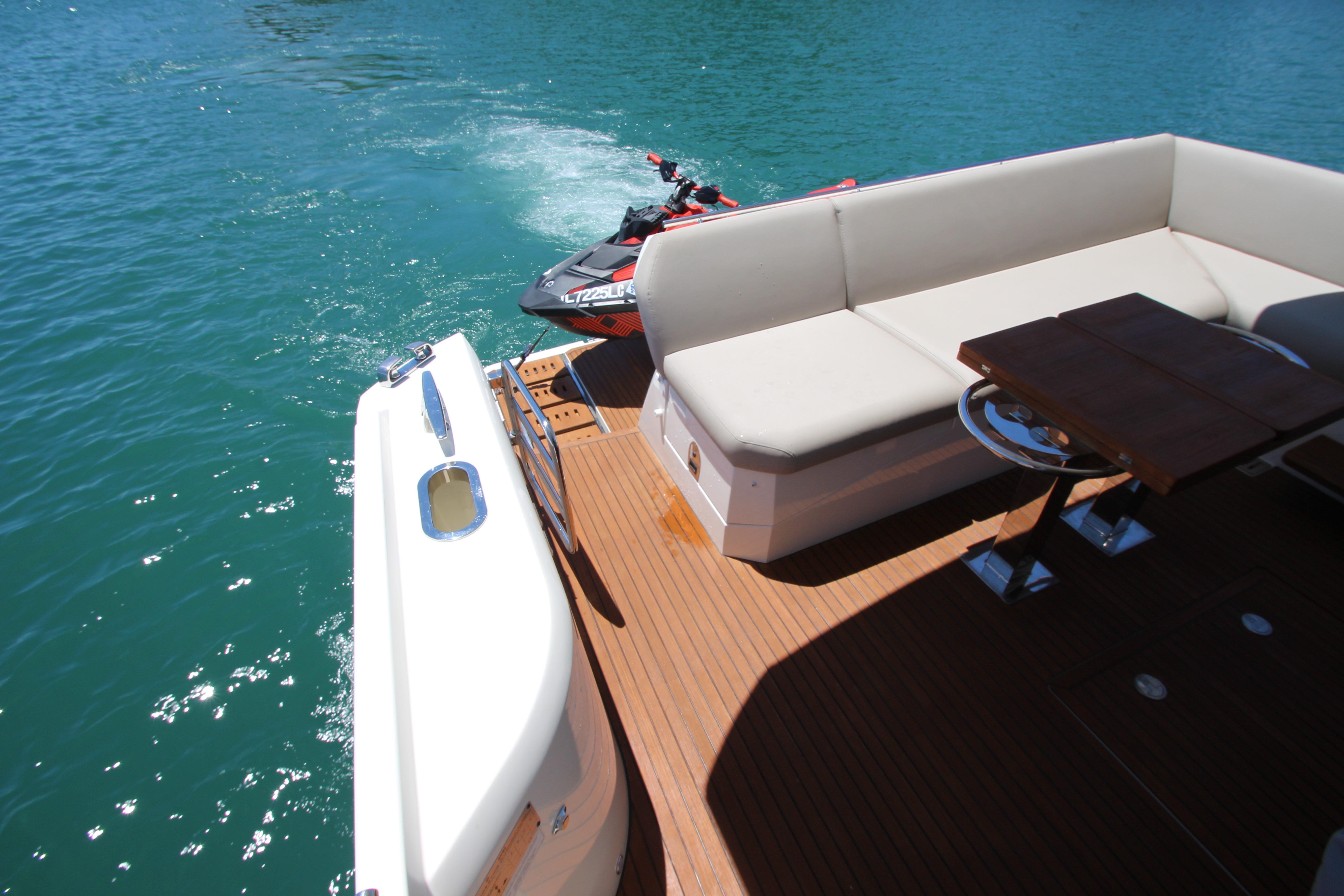 Luxurious 2022 Prestige 520 yacht deck with seating and jet ski on turquoise water.