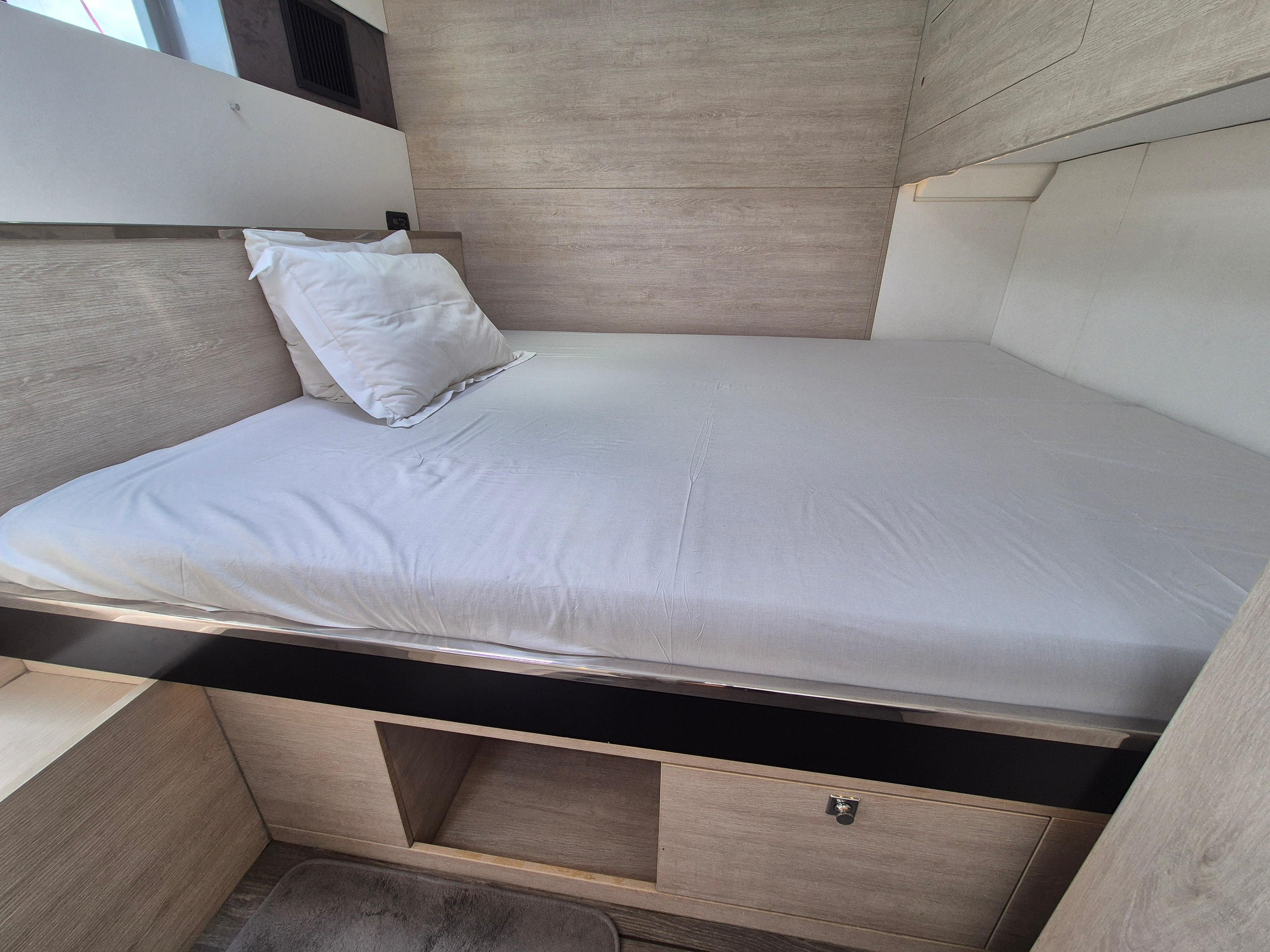 Cozy bed in a 2020 Leopard 50 yacht cabin with modern wood finish.