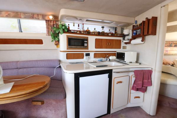 1992 Sea Ray 350 Express Bridge interior kitchen with microwave, fridge, and dining area.