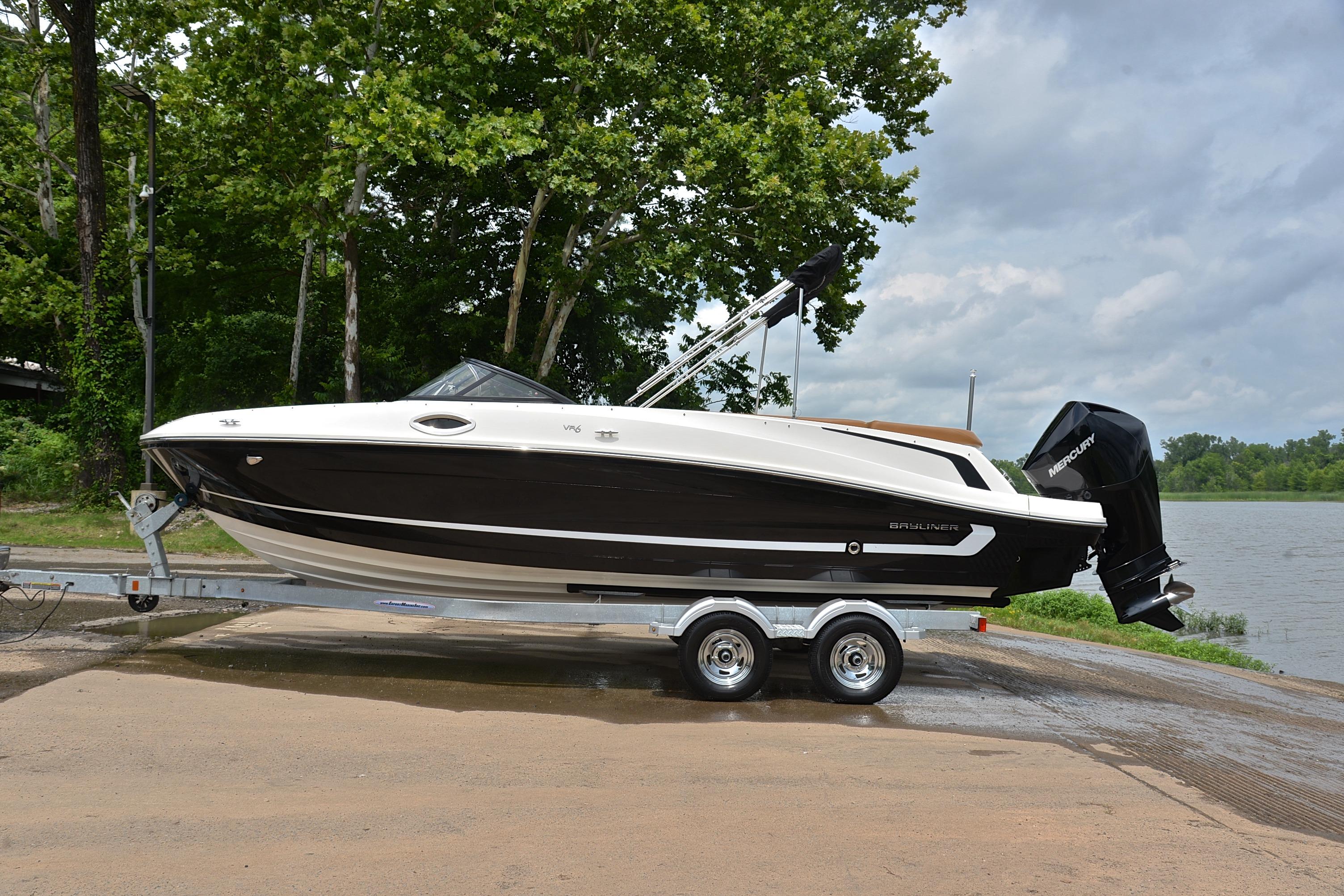 2019 Bayliner VR6 Bowrider OB on trailer by a lakeside, surrounded by trees.