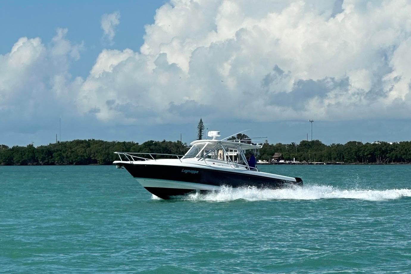 2005 Intrepid 348 Walkaround boat cruising on turquoise water under a cloudy sky.