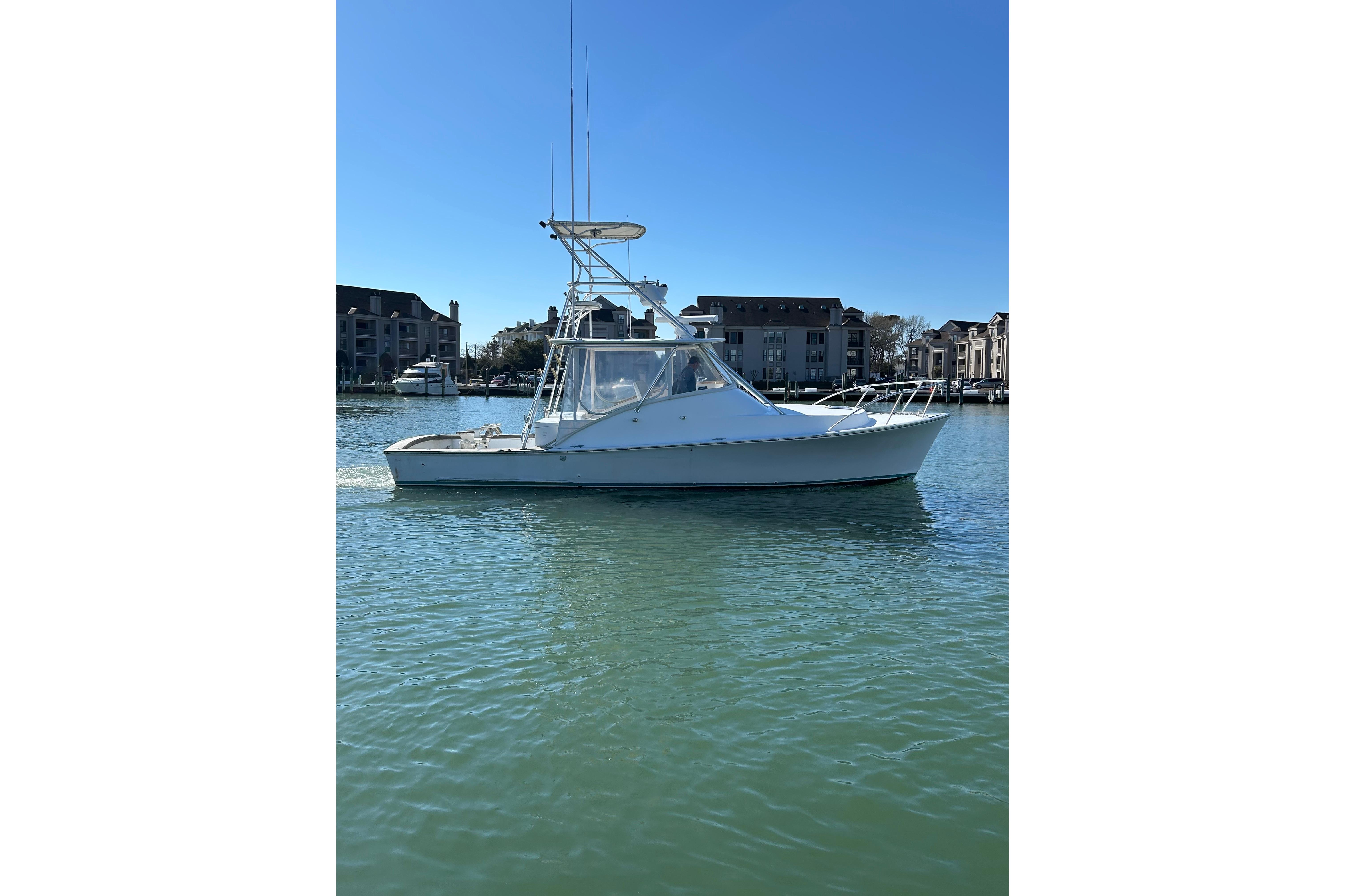 1992 Blue Fin 36 Express boat on calm water near residential buildings.