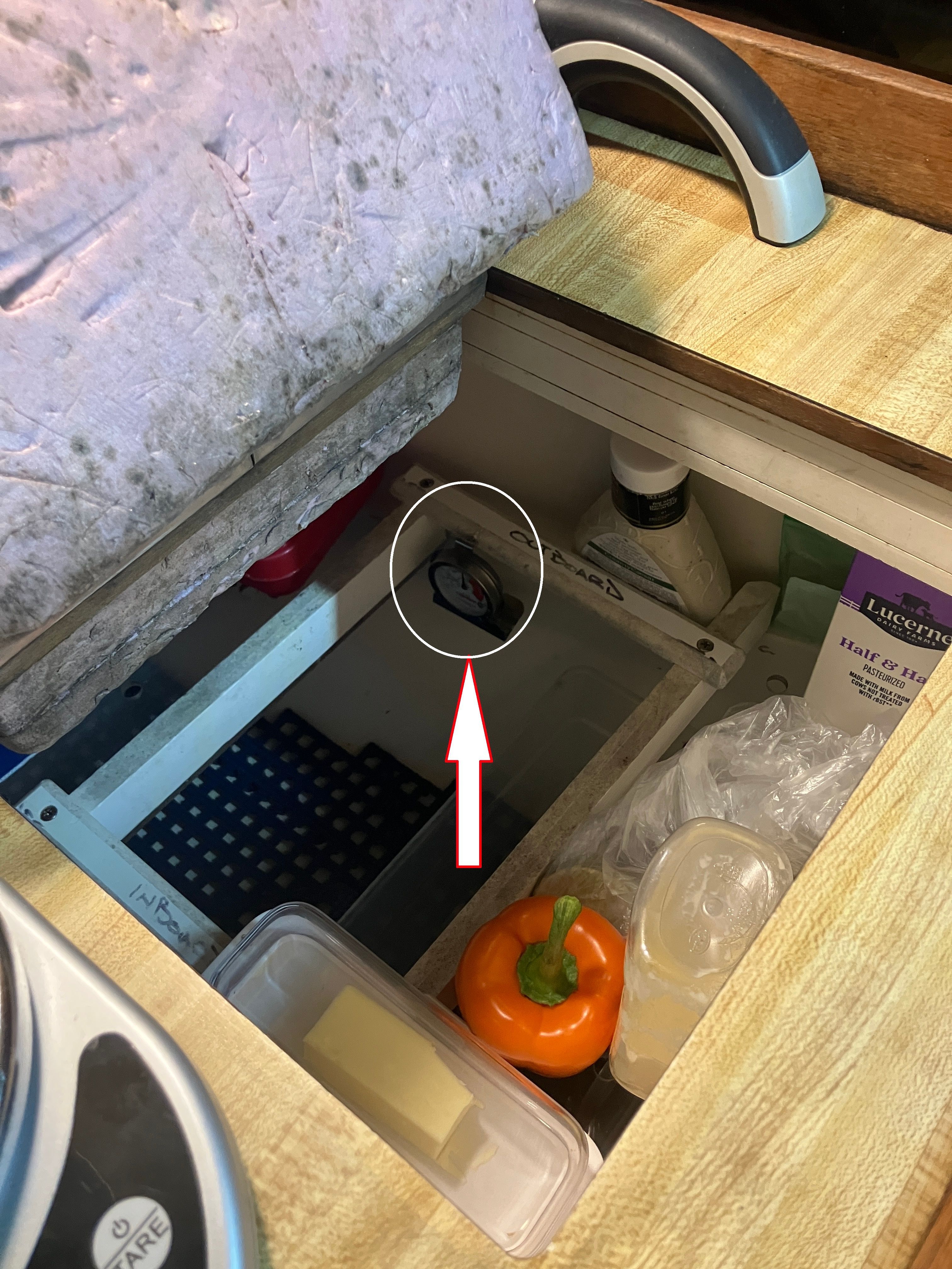 An open compartment in a 1984 Catalina 30 reveals food items and household supplies.
