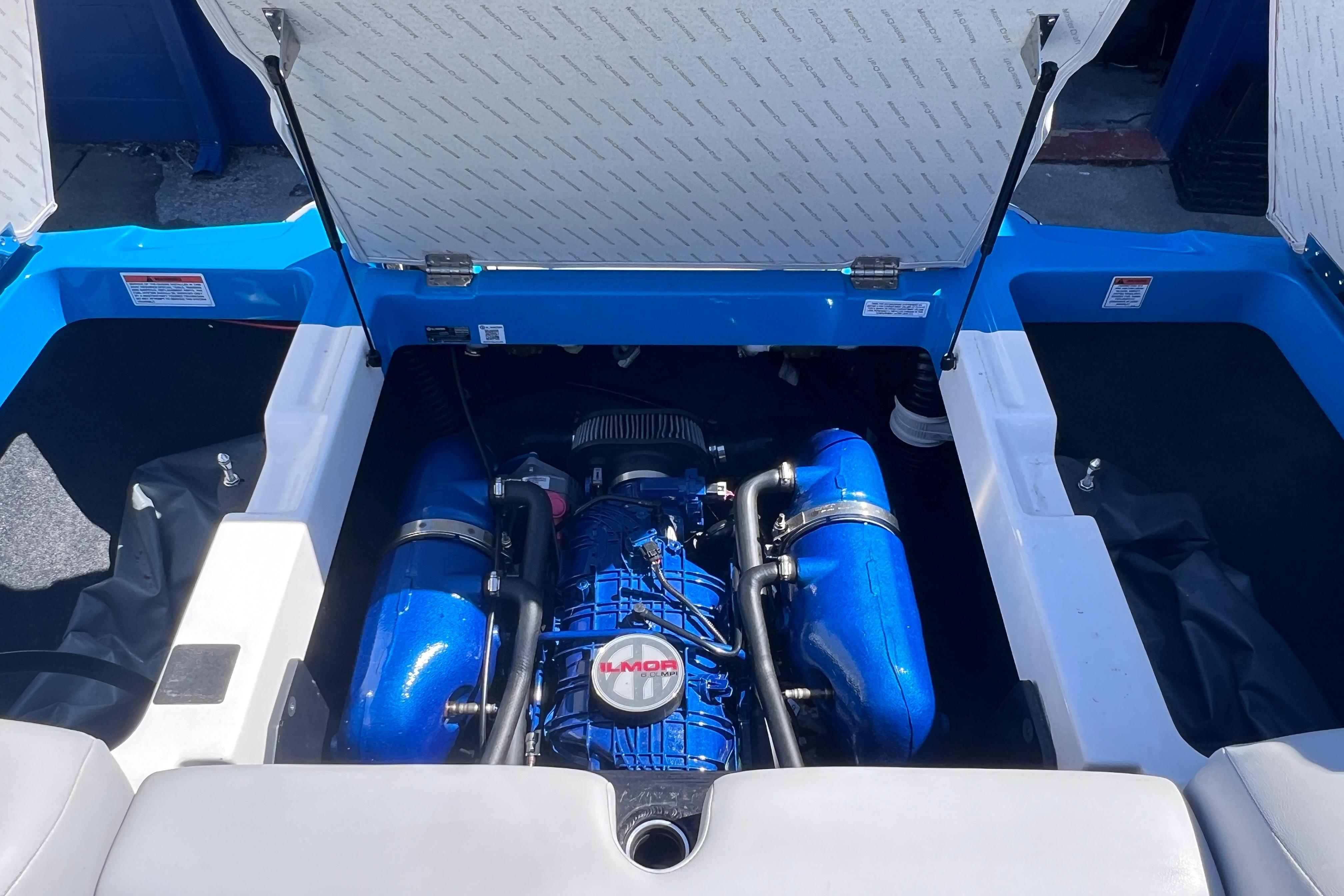 2021 MasterCraft XT23 boat engine compartment with Ilmor engine, blue and white interior.