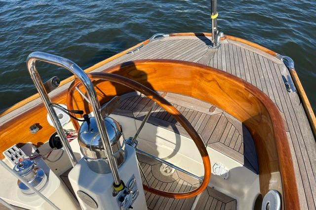 Steering wheel of a 2006 Morris 36 sailboat with wooden accents on deck.