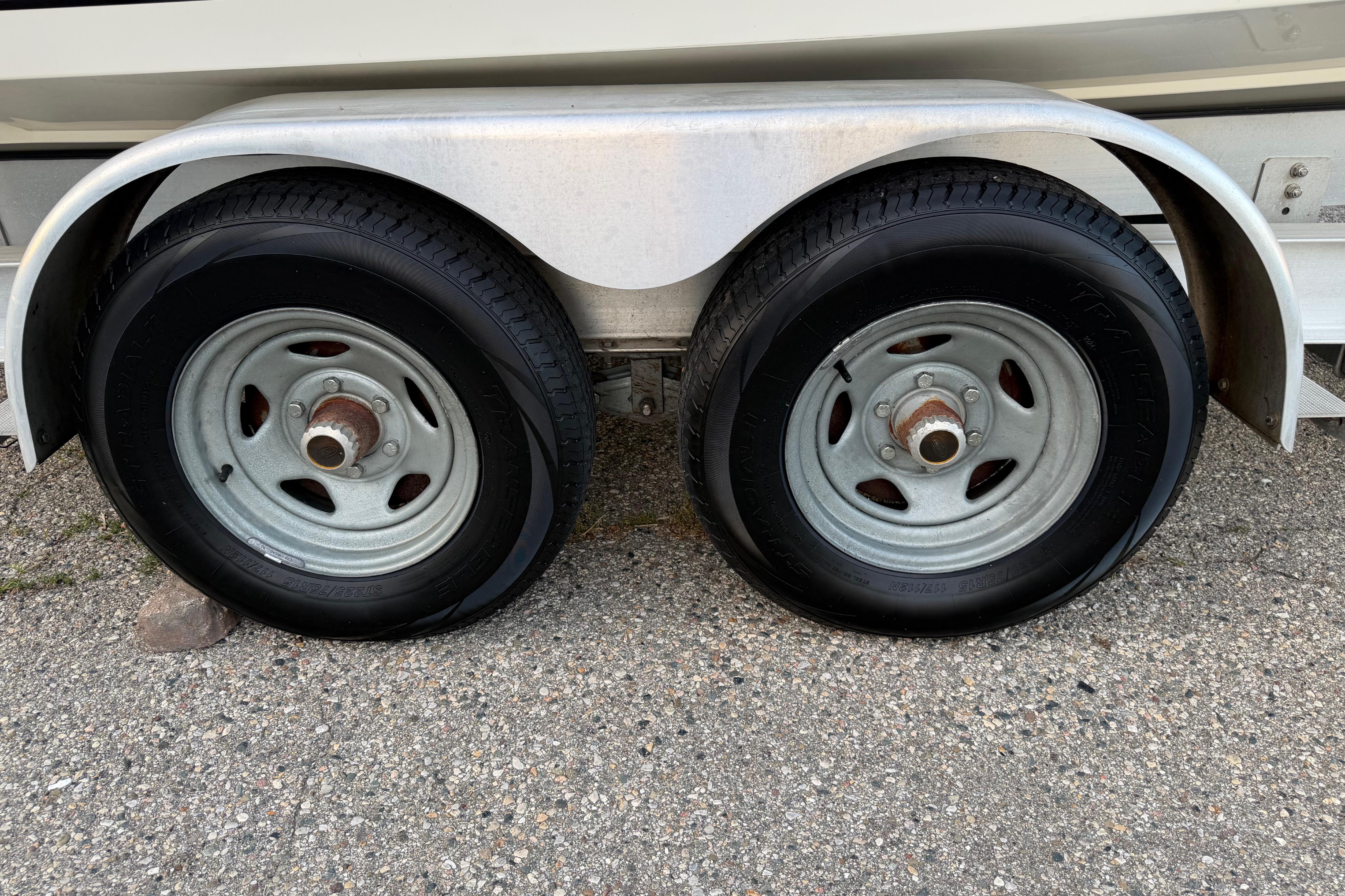 Trailer wheels of a 2007 Mako 234 Center Console boat on pavement.