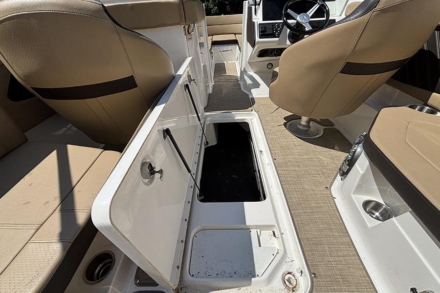 2019 Sea Ray SPX 230 Outboard interior with open storage compartment and beige seating.