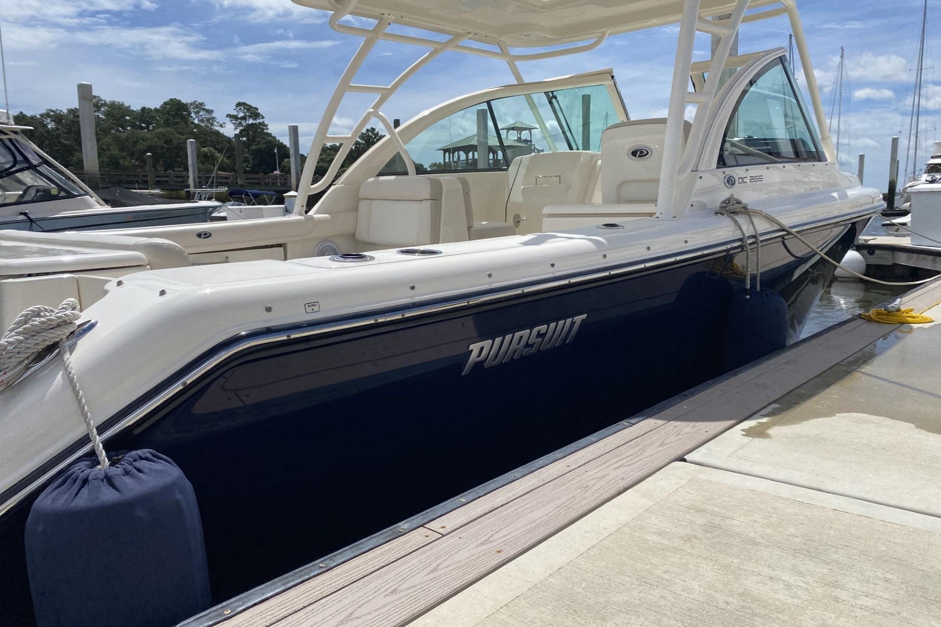 2013 Pursuit DC 265 Dual Console boat docked at marina under clear sky.