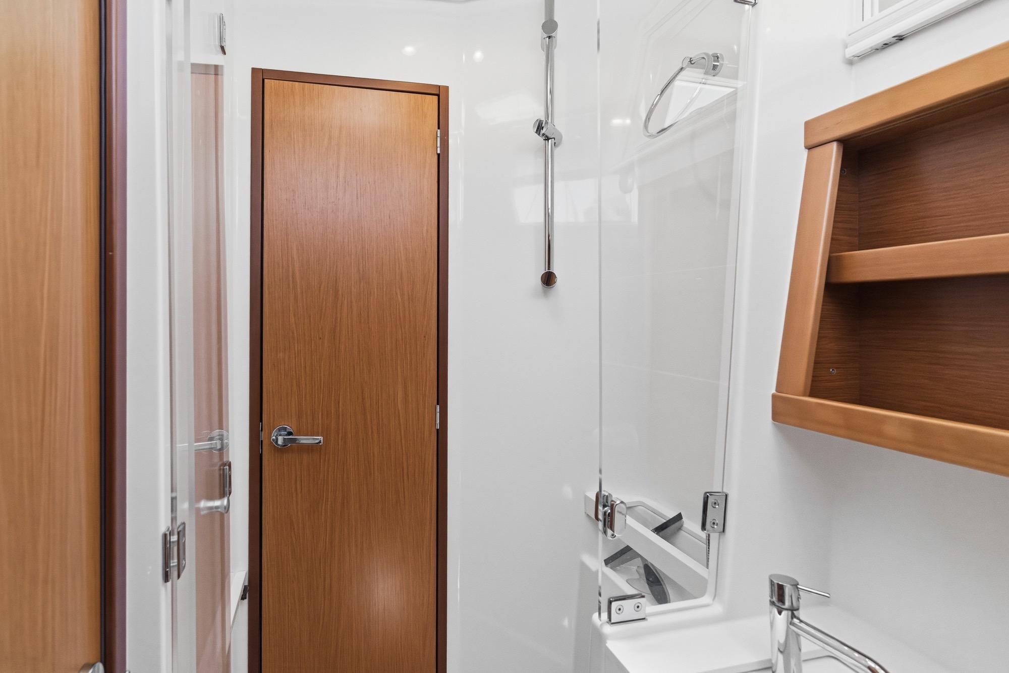 Bathroom interior of 2017 Beneteau Sense 50 yacht, featuring wooden door and modern fixtures.