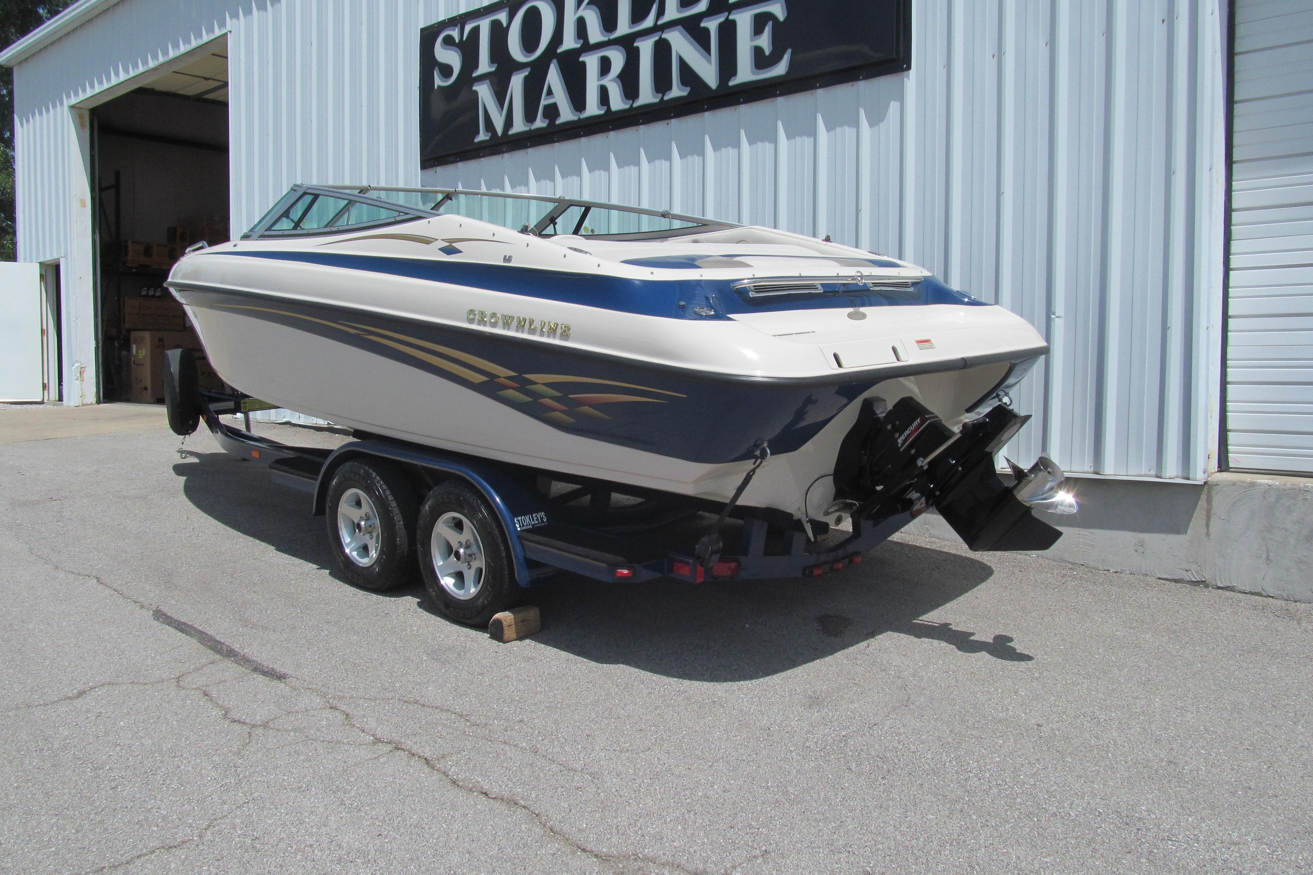 2001 Crownline 225 BR boat on trailer outside marine store.