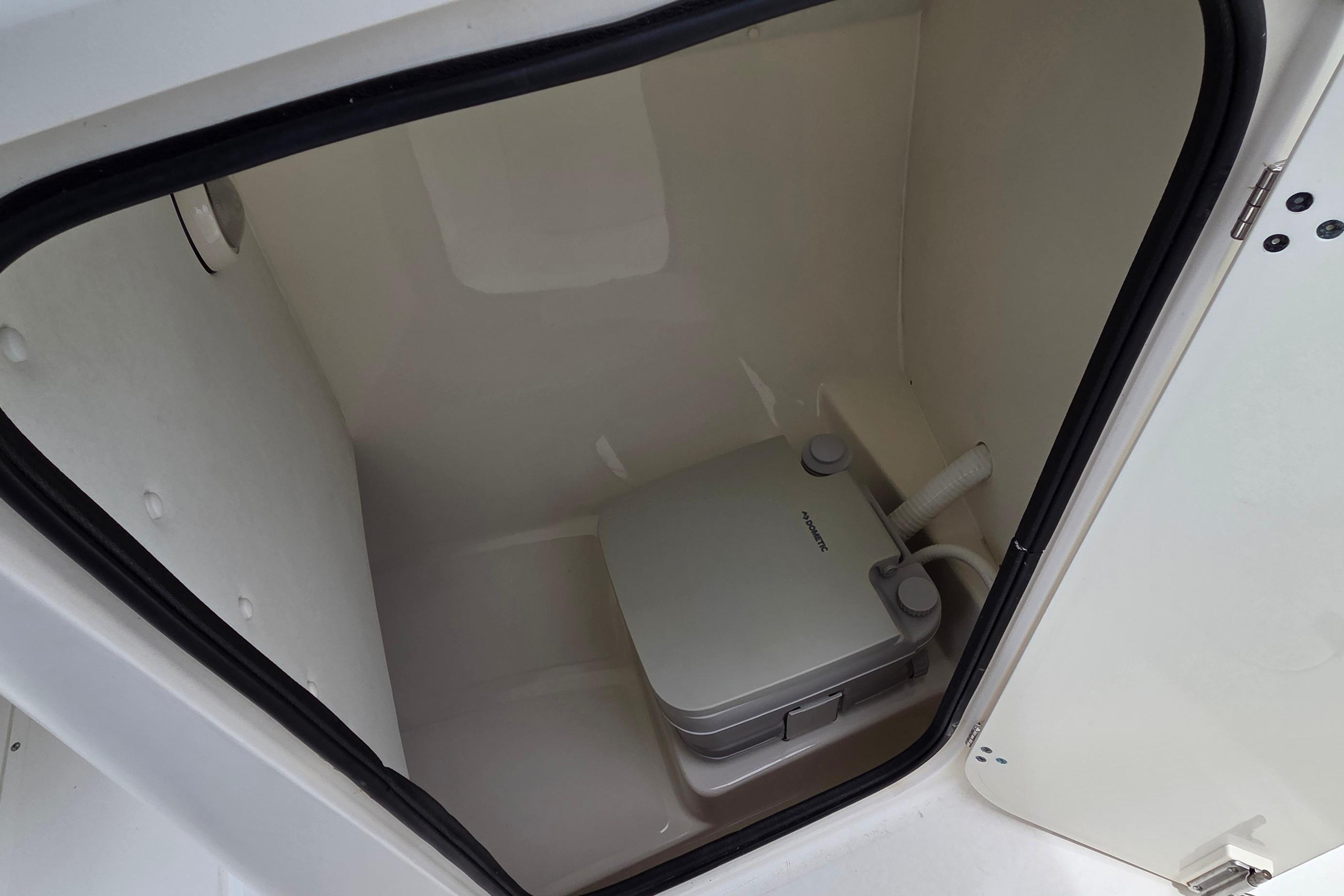 Portable toilet inside 2000 Boston Whaler 21 Ventura boat compartment.