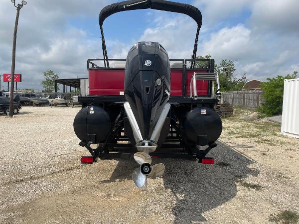 2023 Regency 250DL3 pontoon boat with powerful outboard motor, parked on gravel lot.