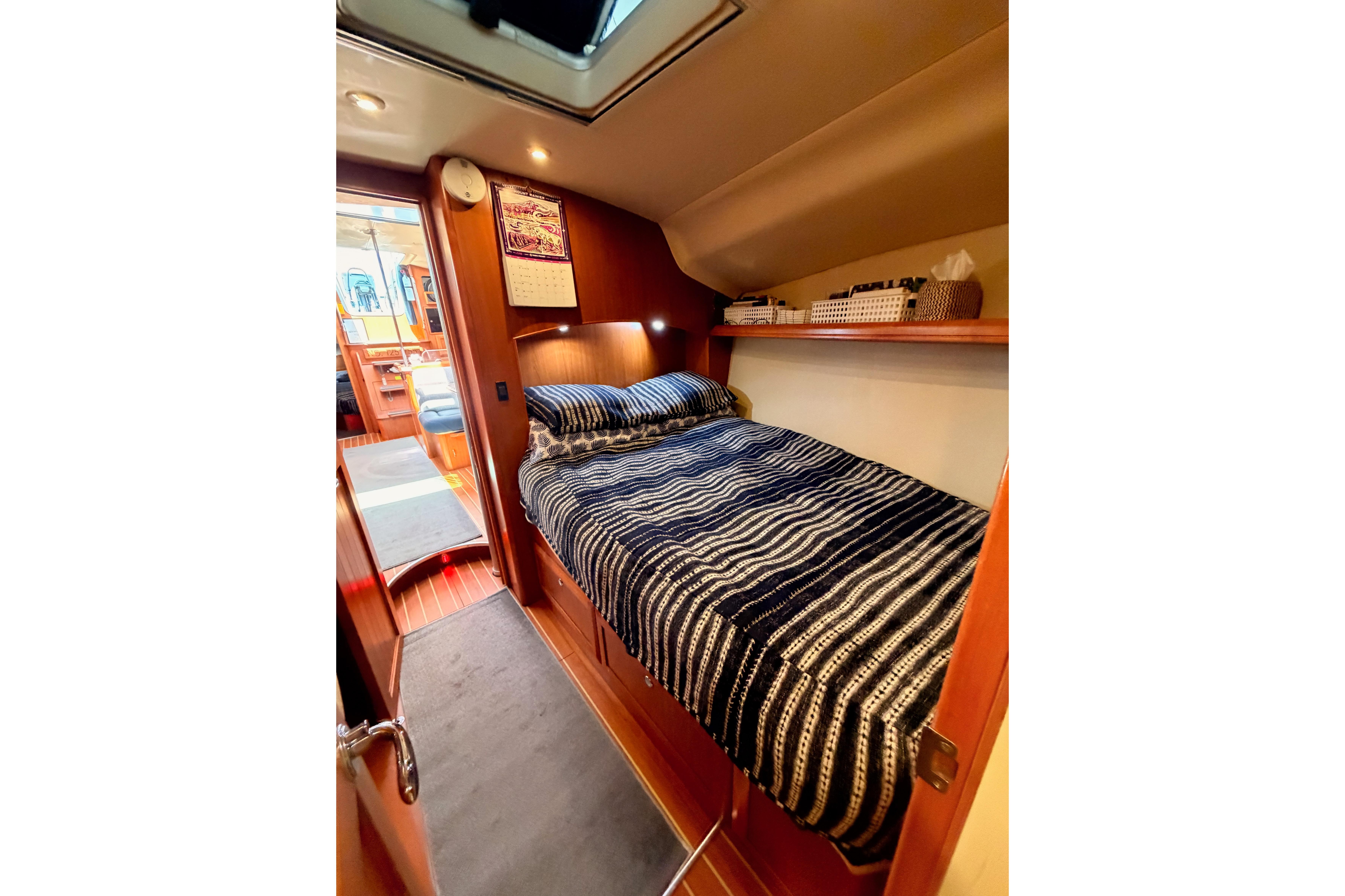 Cozy cabin interior of 2008 Hunter 45 Deck Salon yacht with striped bedding.