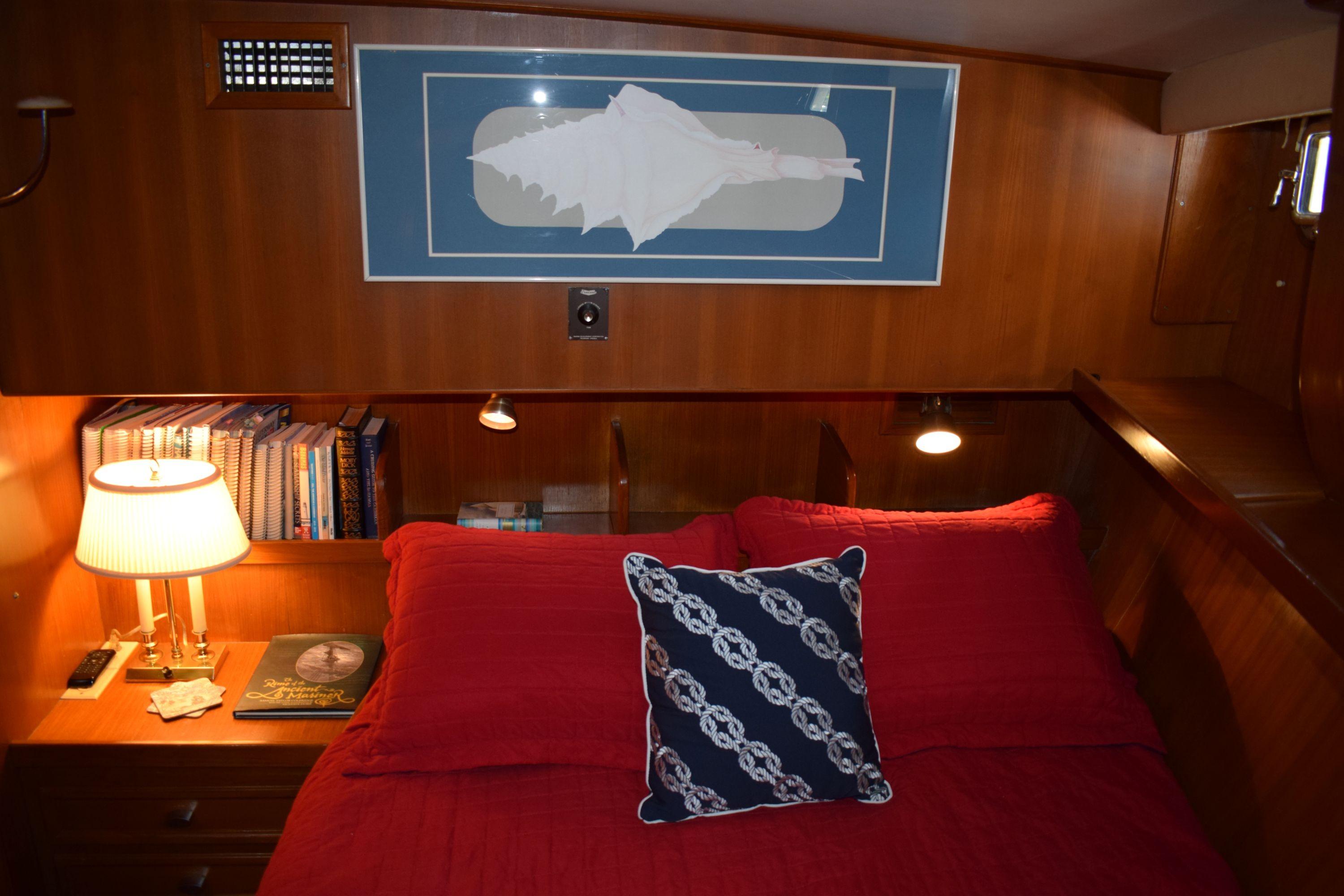 Cozy cabin interior of 1980 Cheoy Lee 52 Motorsailer with red bedding and nautical decor.