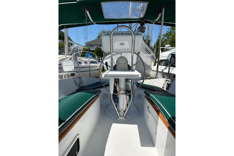 Cockpit view of 2000 Beneteau Oceanis 321 sailboat with green seating and steering wheel.
