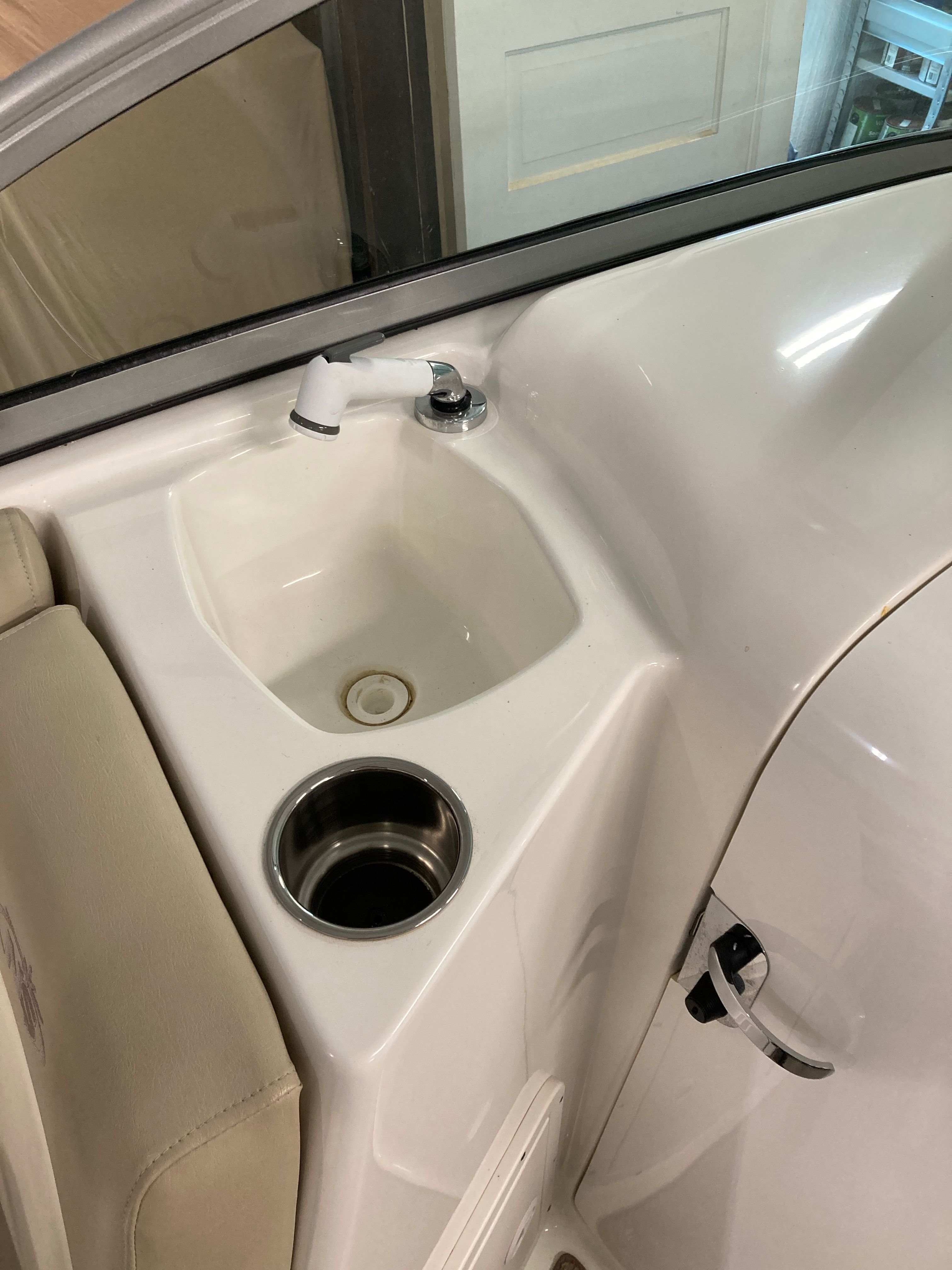 A sink with a faucet and cup holder on a boat.