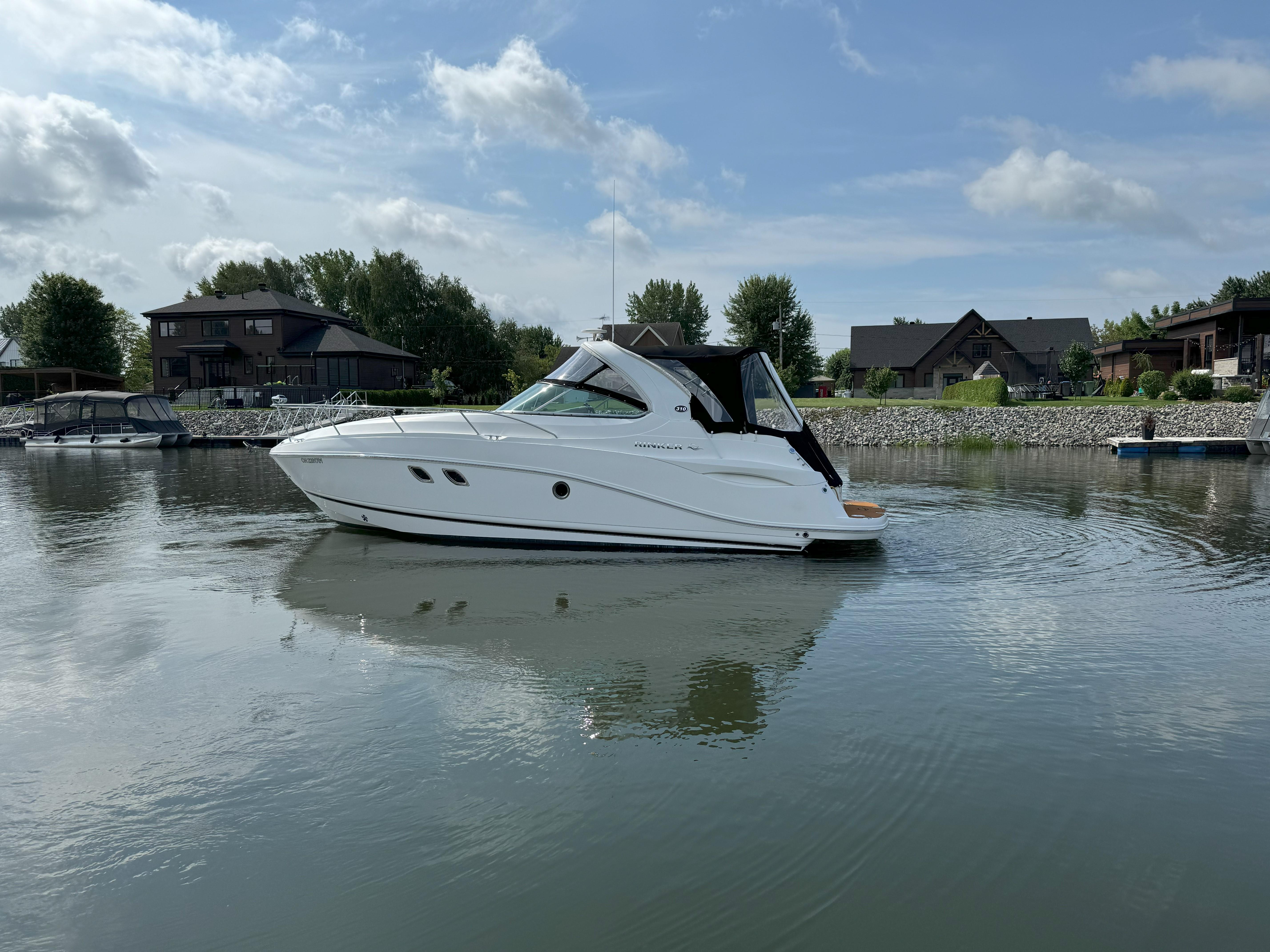 2010 Rinker 310 Express Cruiser on calm water near docks.