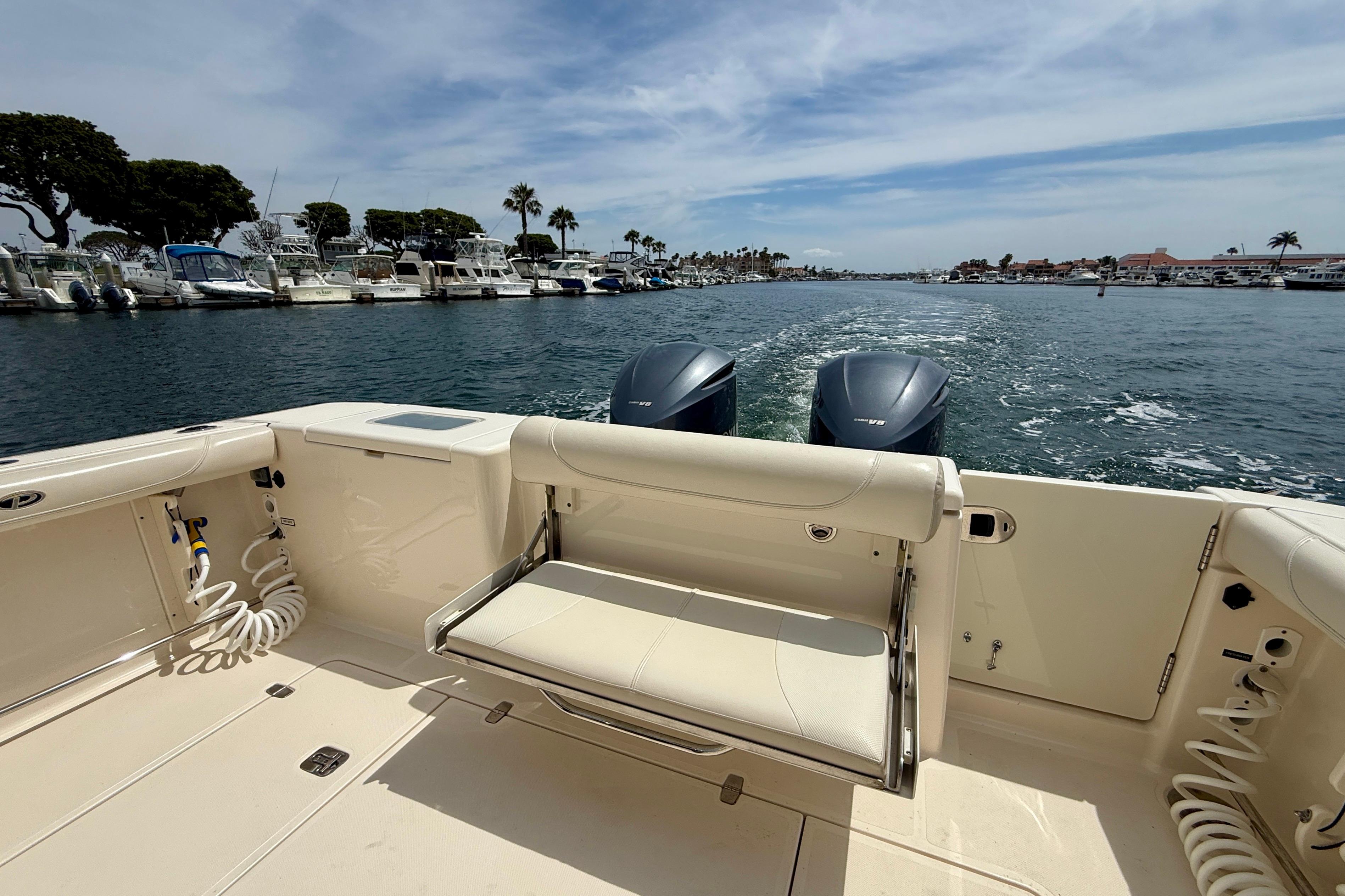 2012 Pursuit OS 345 Offshore boat cruising on a sunny day, with twin engines visible.