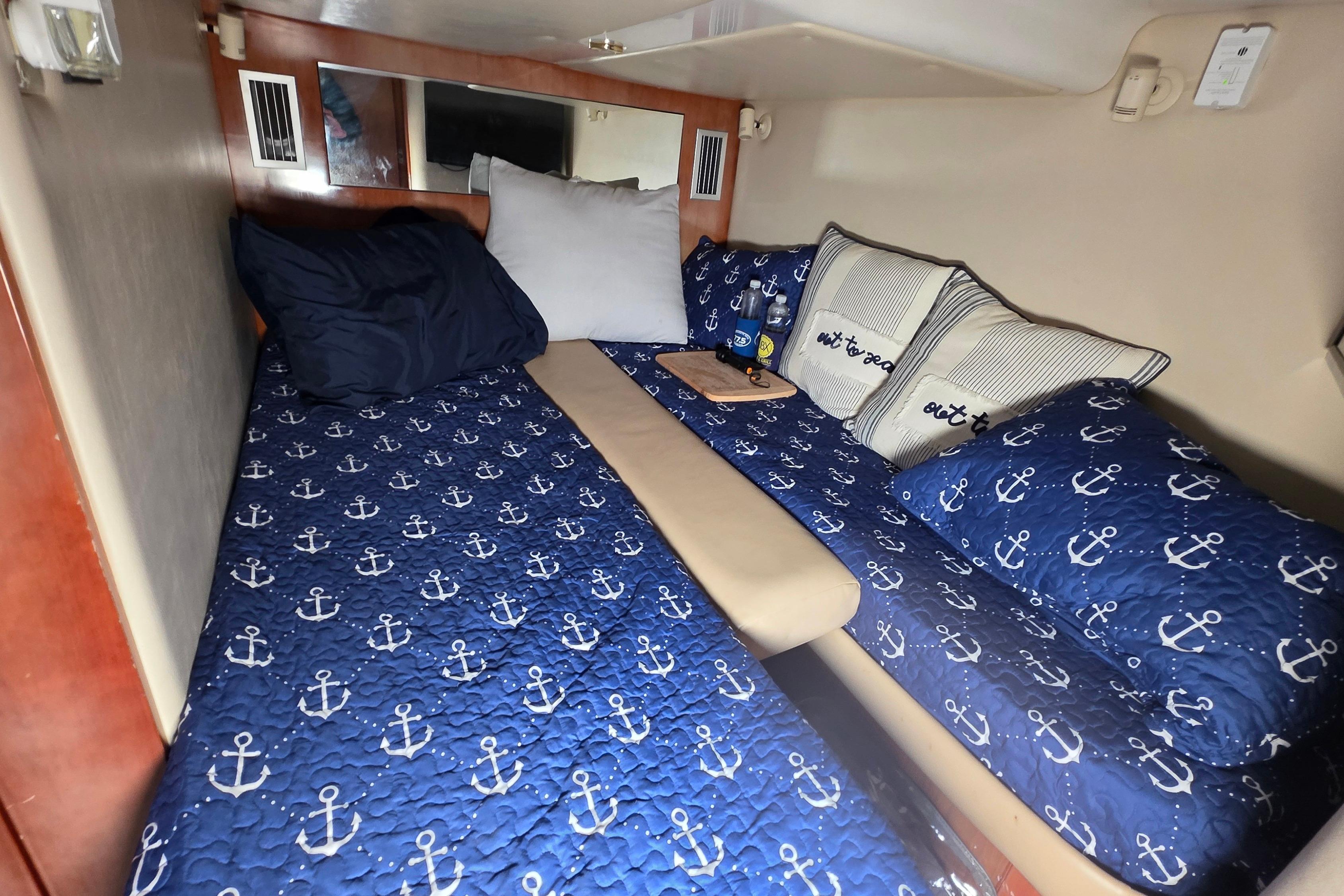 Cozy cabin interior of 2002 Regal Commodore 4260 with nautical-themed bedding.